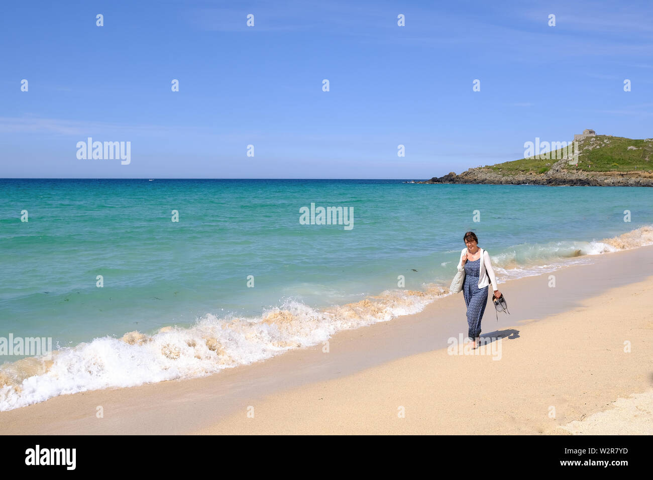 A woman walking along the shore on a beautiful beach at St Ives in Cornwall Stock Photo