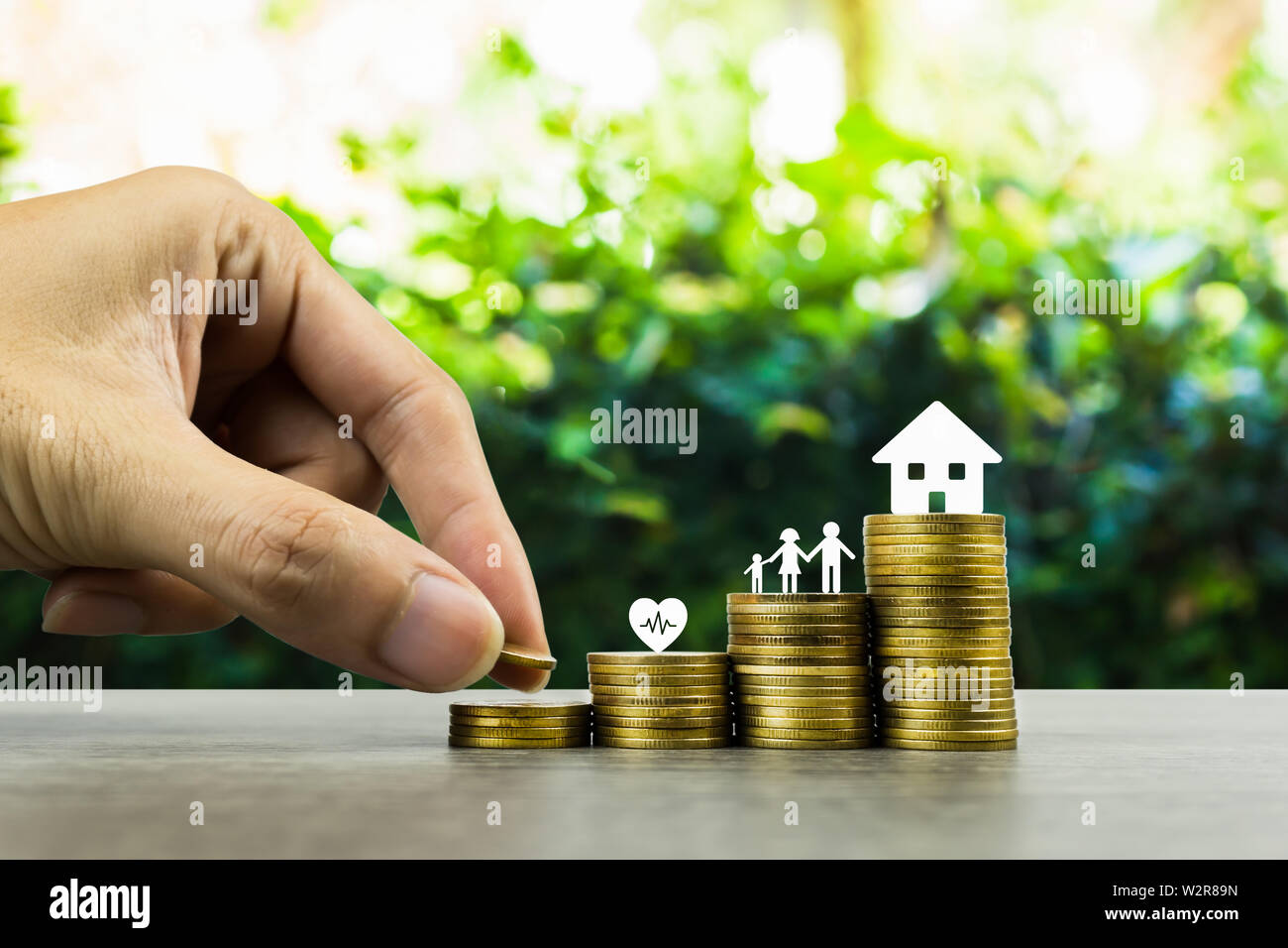 Saving or making money for family life in future concept. A man hand  putting coin into rising stack of coins with heart, family and small house  model Stock Photo - Alamy