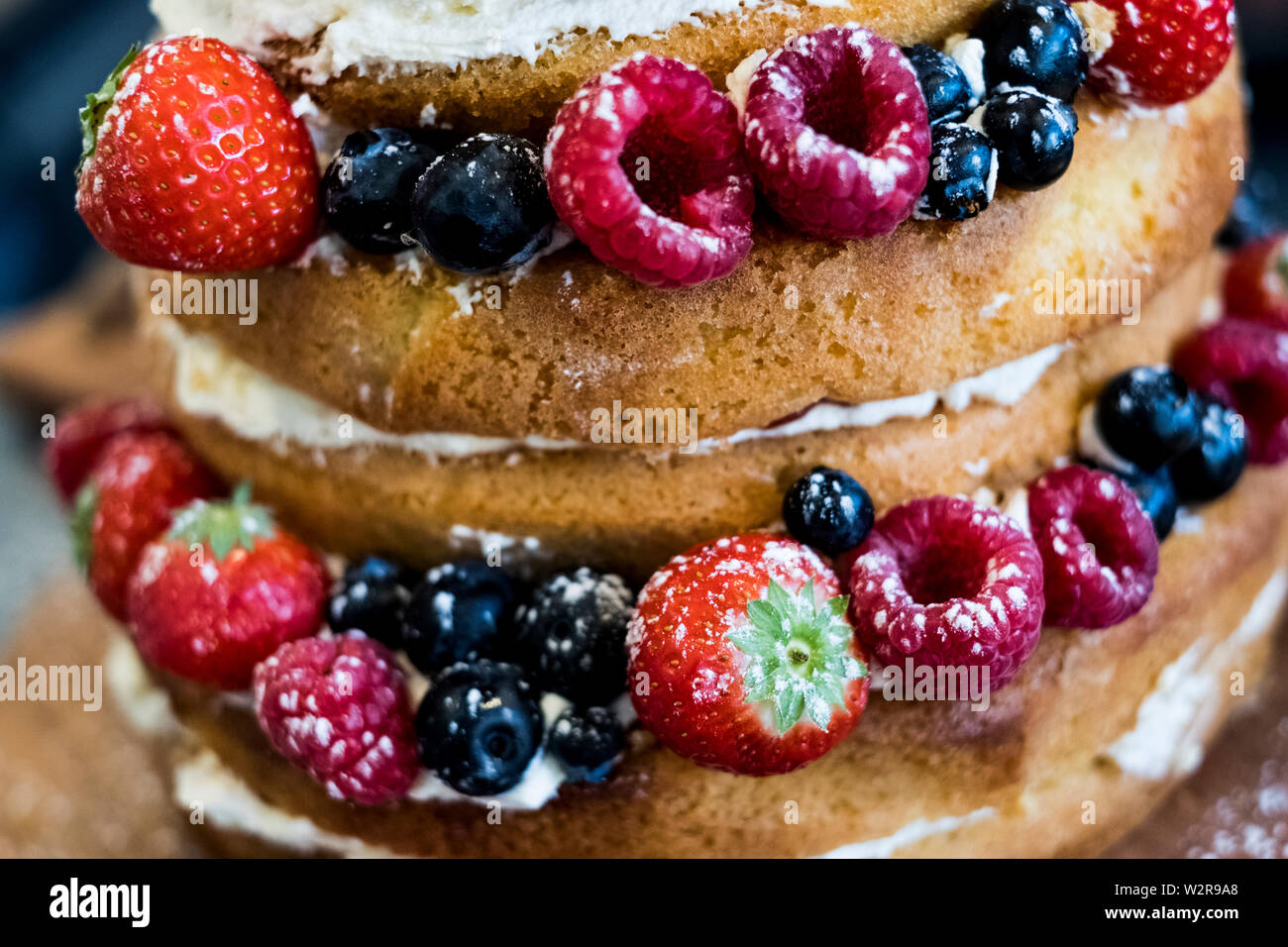 Close up of a freshly baked sponge cake layered with fresh cream and fresh fruit. Stock Photo