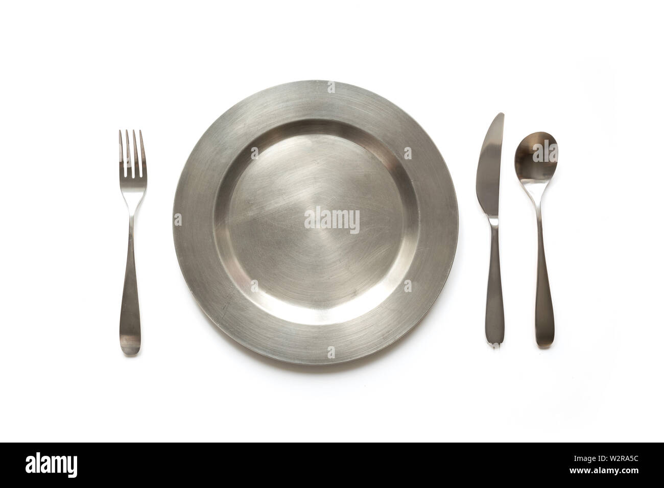 Empty metal dish with knife and fork on white background, with copy space. Table setting. Stock Photo