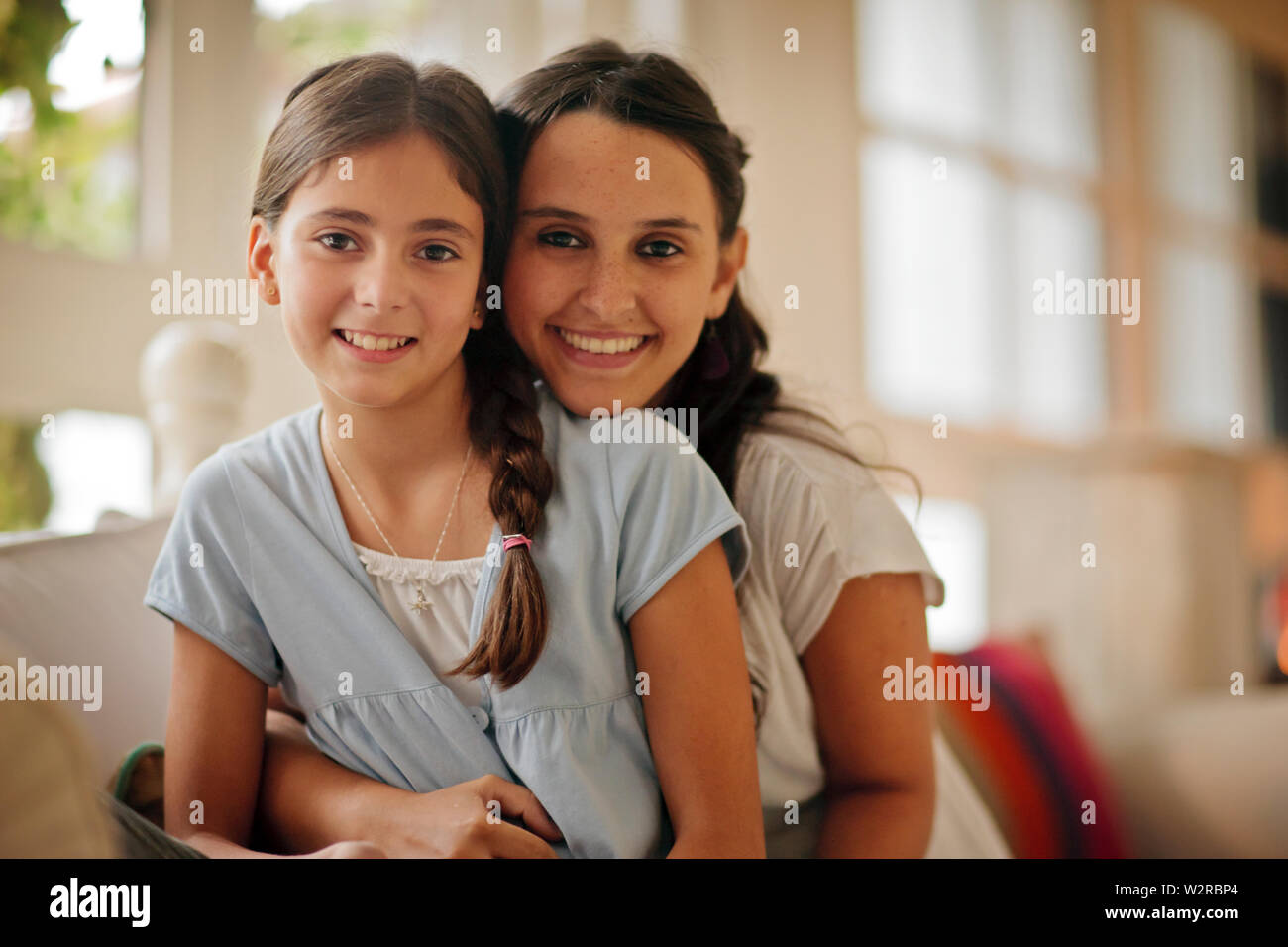 Portrait of two sisters sitting on sofa Stock Photo - Alamy