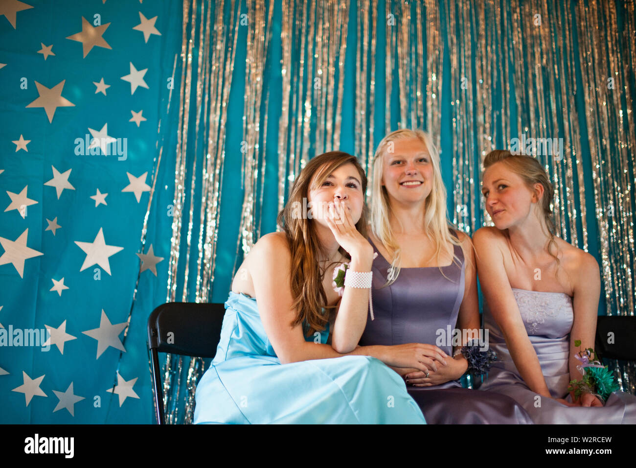Three teenage girls sitting and smiling at prom. Stock Photo
