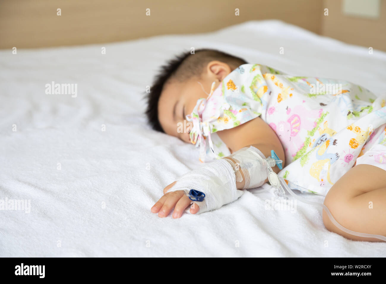 Asian baby boy sleeping on bed with infusion set at child department in the hospital. Children with infectious diseases IPD, Invasive Pneumococcal Dis Stock Photo