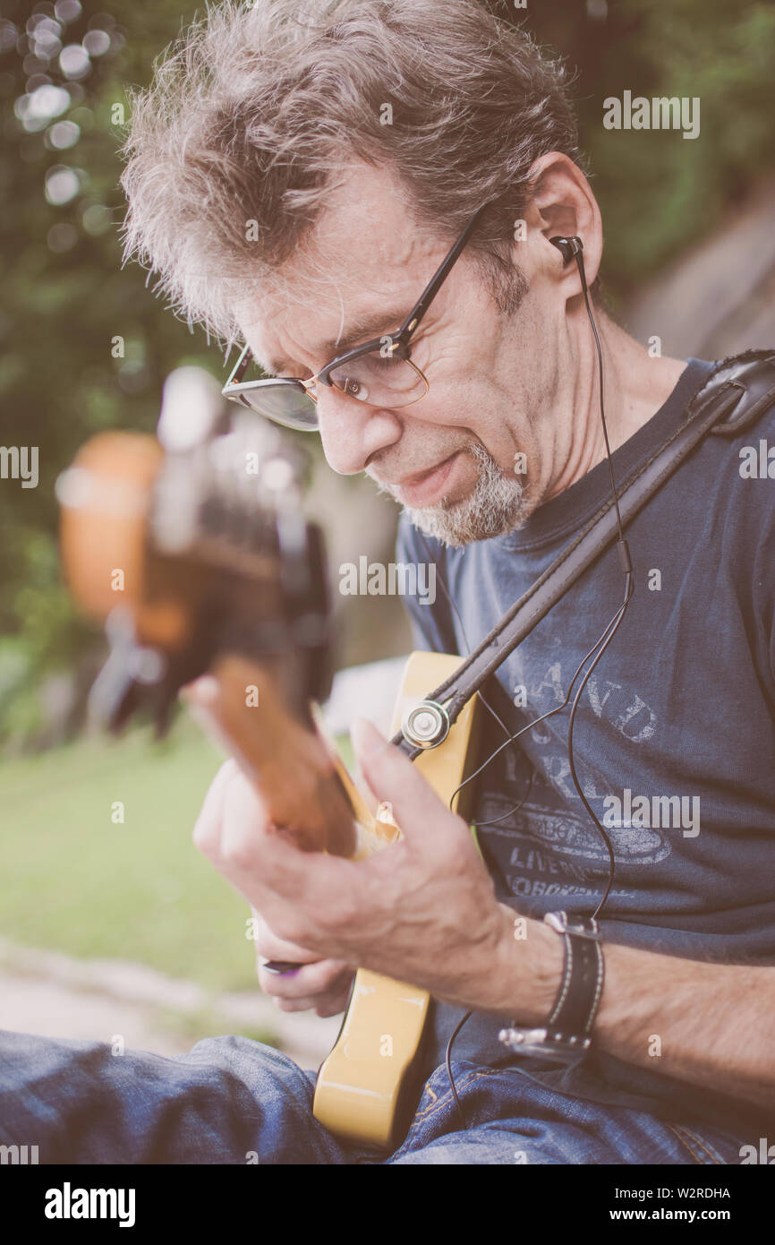 Older male musician playing guitar on a New York City Street Stock Photo