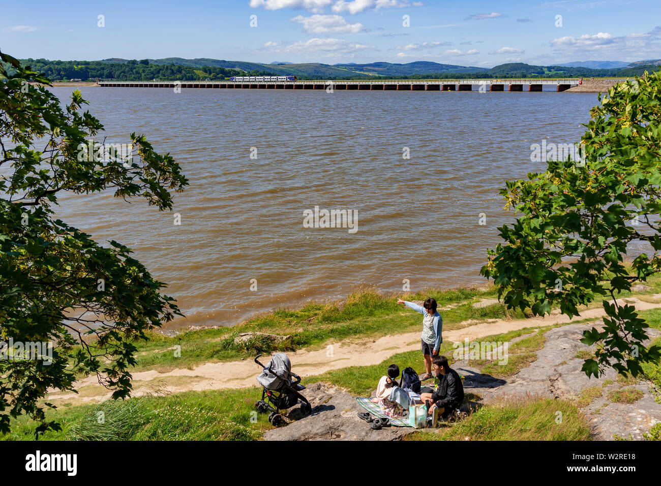The railway viaduct over the river Kent at Arnside in Cumbria with picnicking family. Stock Photo