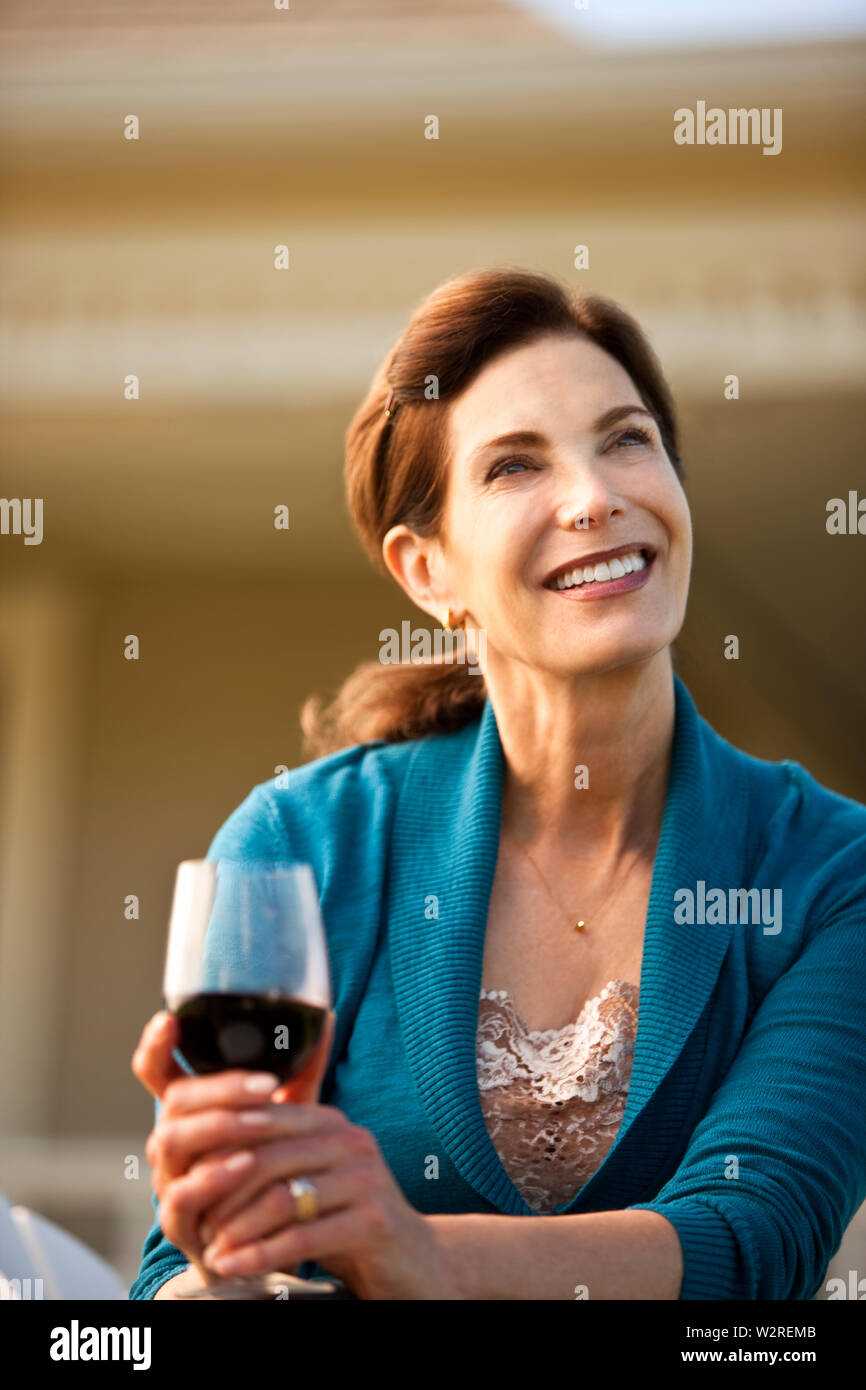 Mature woman enjoys glass of red wine in her backyard Stock Photo - Alamy