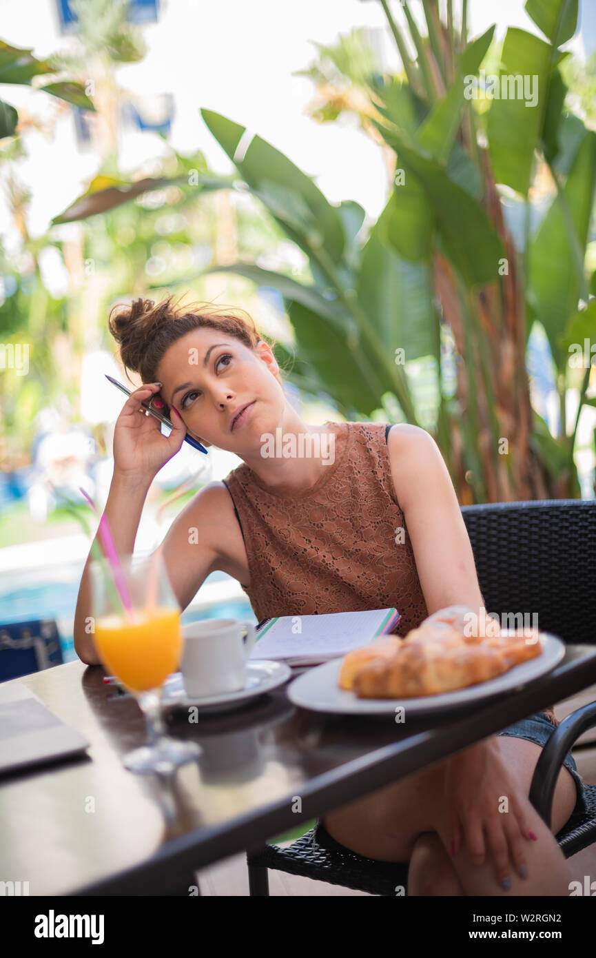 Gorgeous tourist working on the terrace - Espresso coffee snack, bread rolls and orange juice - Adorable woman looking at the sky Stock Photo