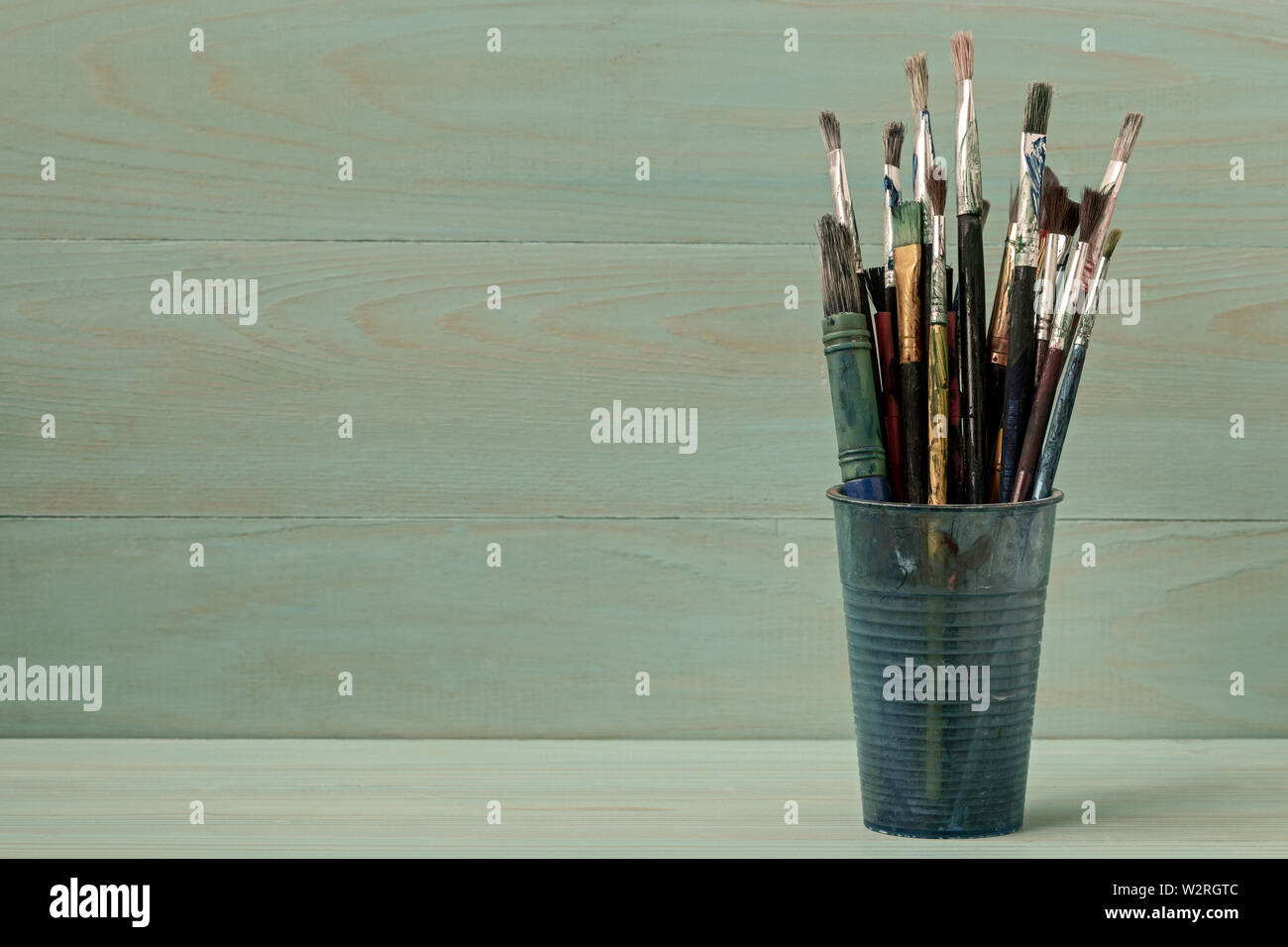 Assorted dirty painting brushes in plastic flask Stock Photo