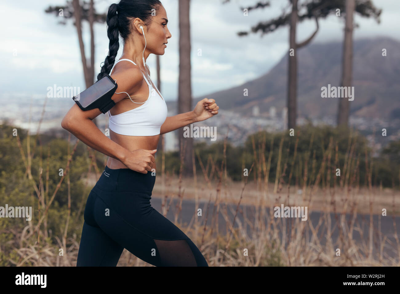 Woman athlete running on country road early in morning. fitness woman sprinting outdoors. Stock Photo