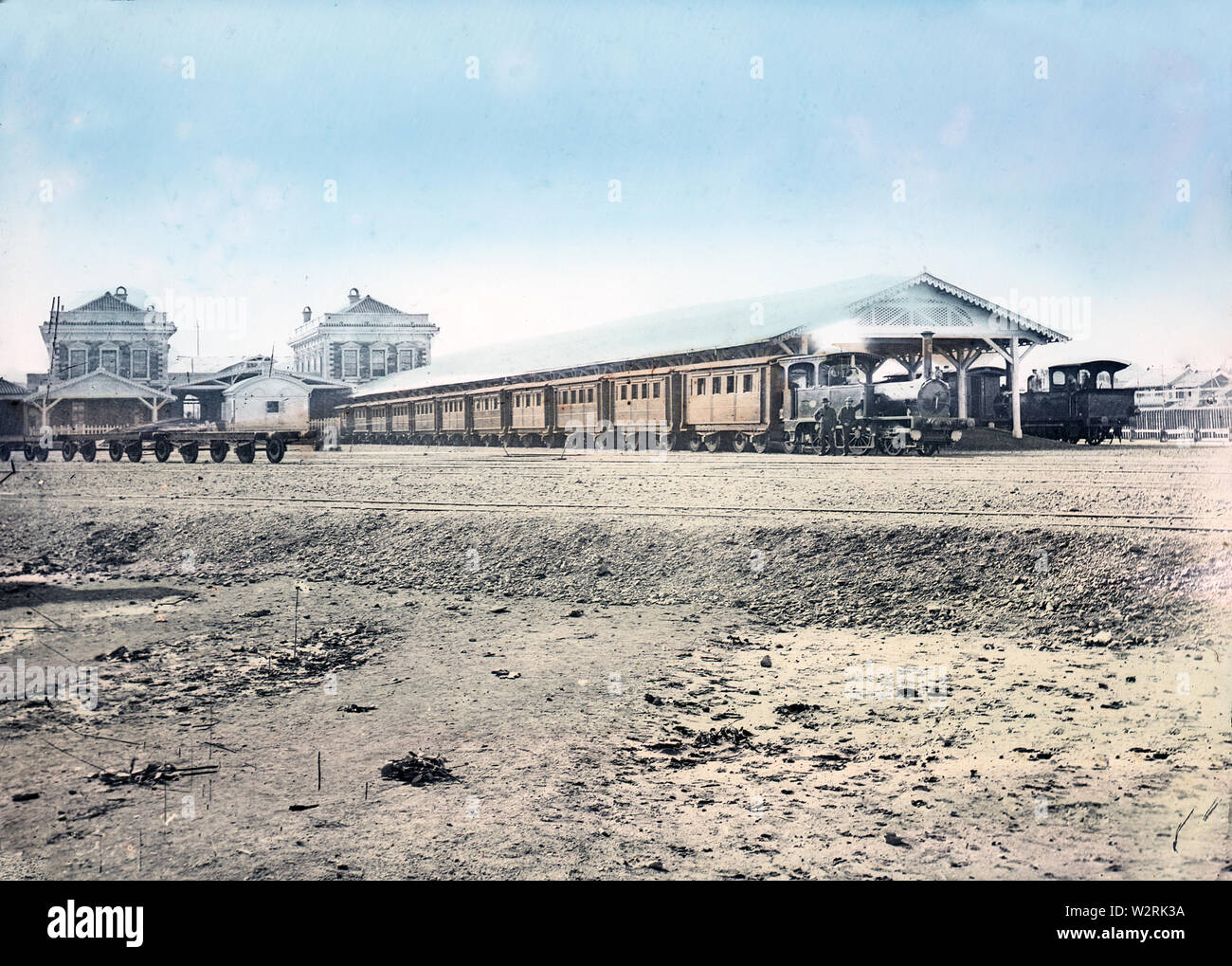 [ 1870s Japan - Train at Shinbashi Station, Tokyo ] —   Two steam trains and passenger cars at Shinbashi (also Shimbashi) Station in Tokyo, ca. 1873-74. This is an extremely rare view because it is photographed shortly after the opening and because almost all photos of this station show the front.  Designed by American architect Richard P. Bridgens (1819-1891), Shinbashi was the original terminus of Japan's first railway, the Tokaido Main Line, connecting Yokohama with Tokyo. It was opened on October 10, 1872 (Meiji 5) and named 'Shinbashi Teishajo'  (新橋停車場).   19th century vintage glass slide Stock Photo