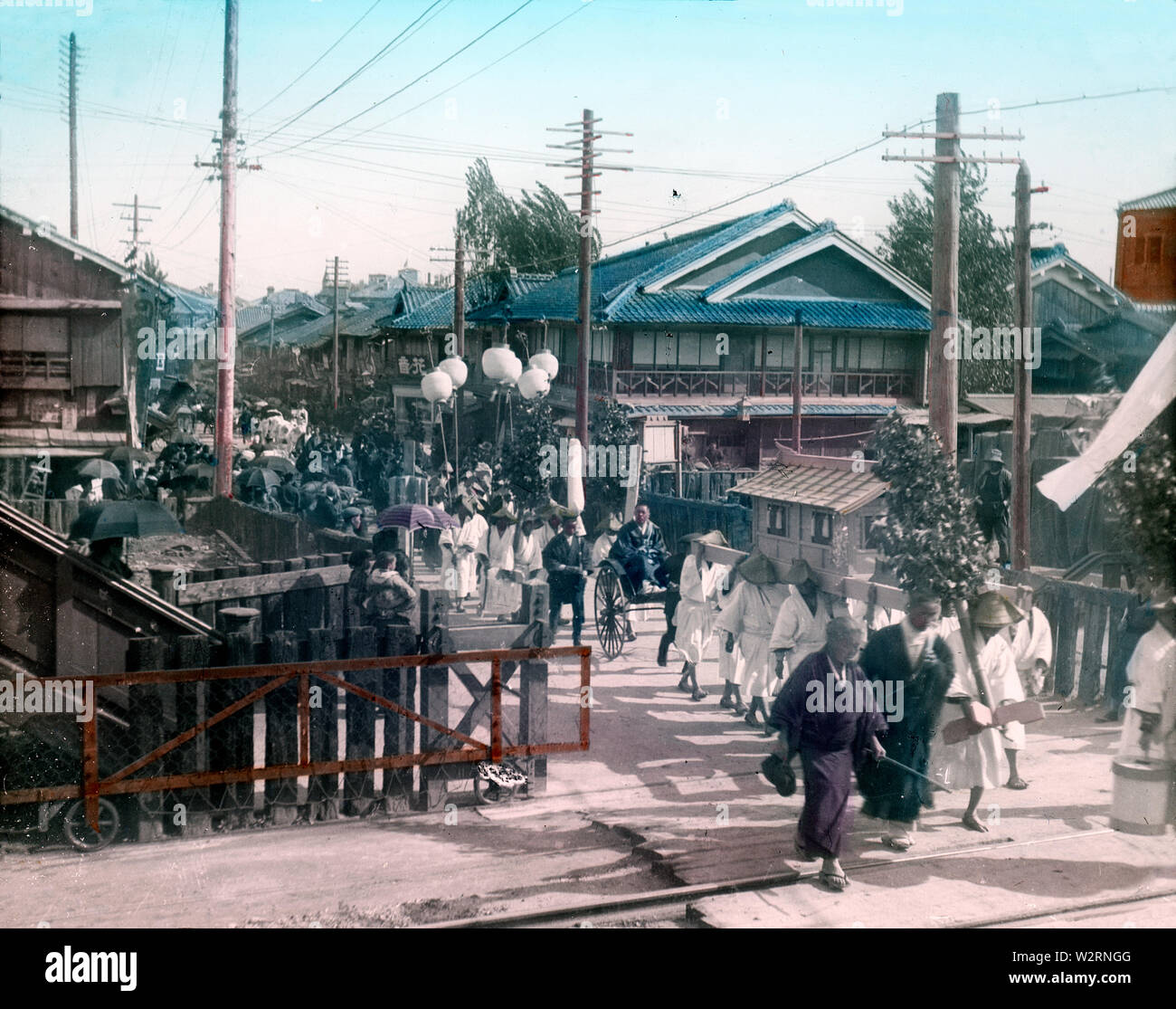 [ 1900s Japan - Japanese Funeral Procession ] —   A funeral procession crosses train tracks. This image can also be found in a book published by Japanese photographer Teijiro Takagi in 1908 (Meiji 41), conveniently dating this image.  20th century vintage glass slide. Stock Photo