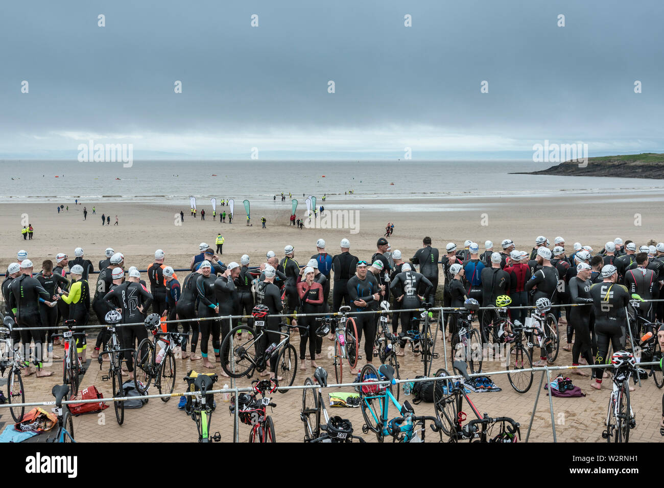 Beneath dark clouds competitors in the 2019 Barry Island sprint triathlon wait on the promenade beside the beach to start their race. Stock Photo