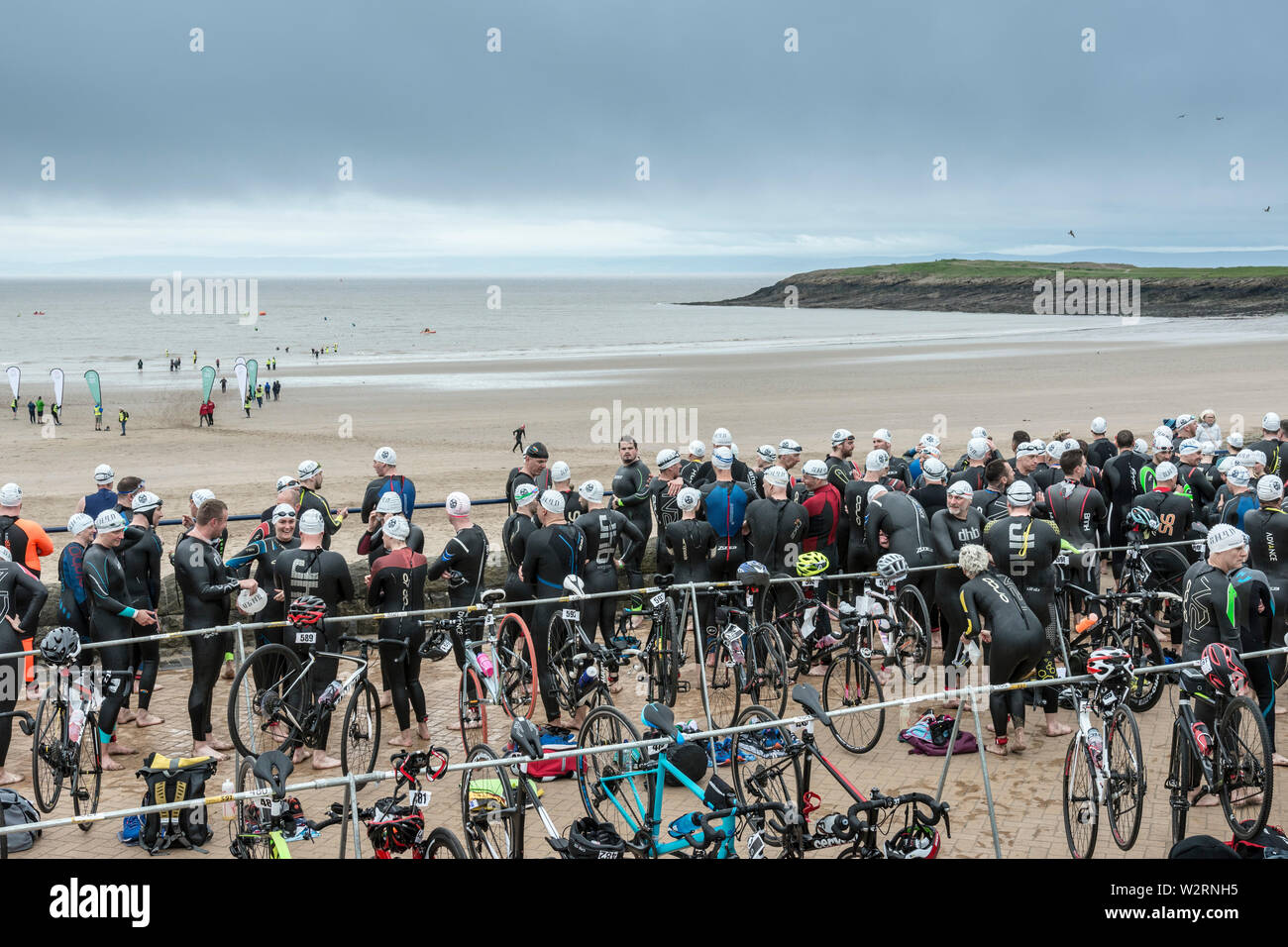 Beneath dark clouds competitors in the 2019 Barry Island sprint triathlon wait on the promenade beside the beach to start their race. Stock Photo