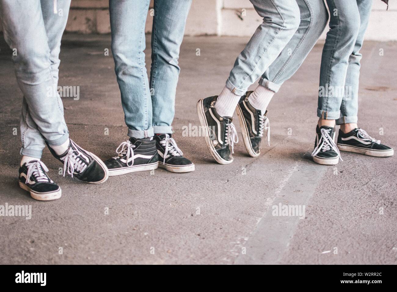 Closeup shot of a group of people wearing old school black vans and blue  jeans Stock Photo - Alamy