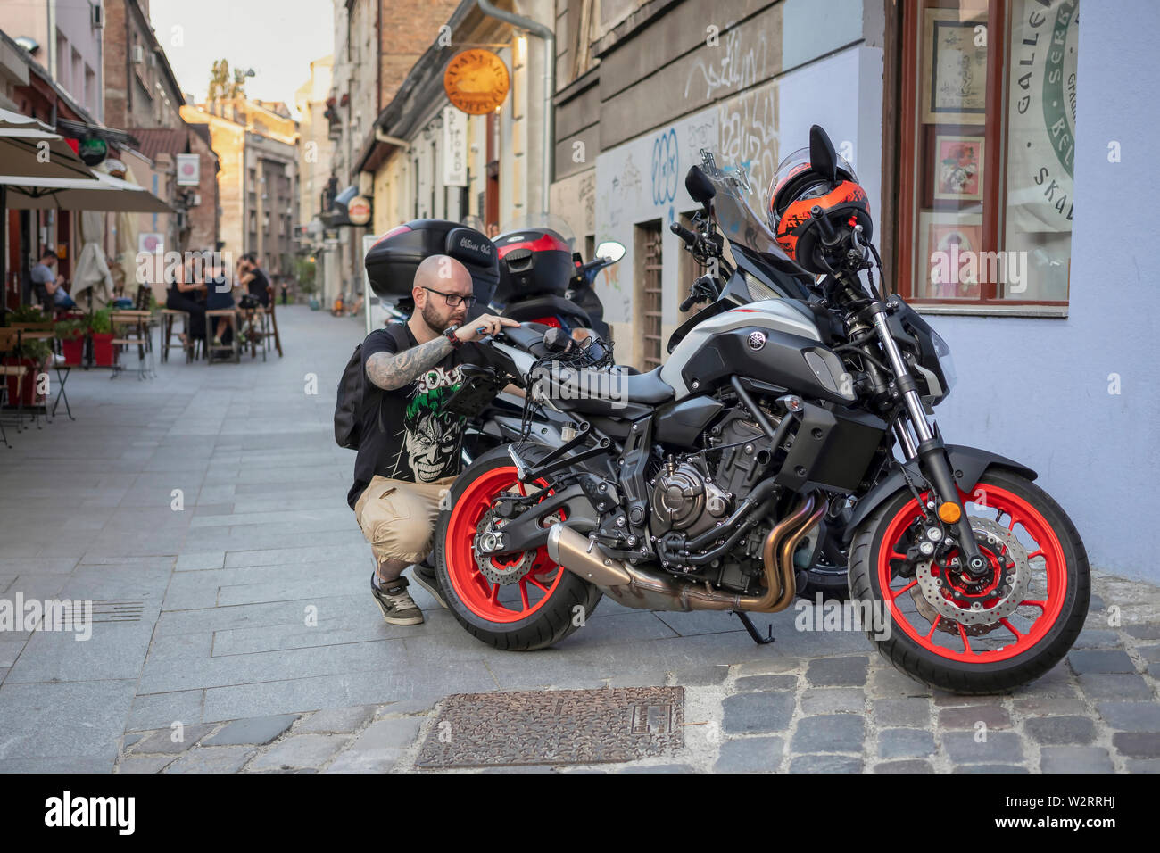 Belgrade, Serbia July 5th 2019: Urban scene with man preparing for a motorbike ride Stock Photo