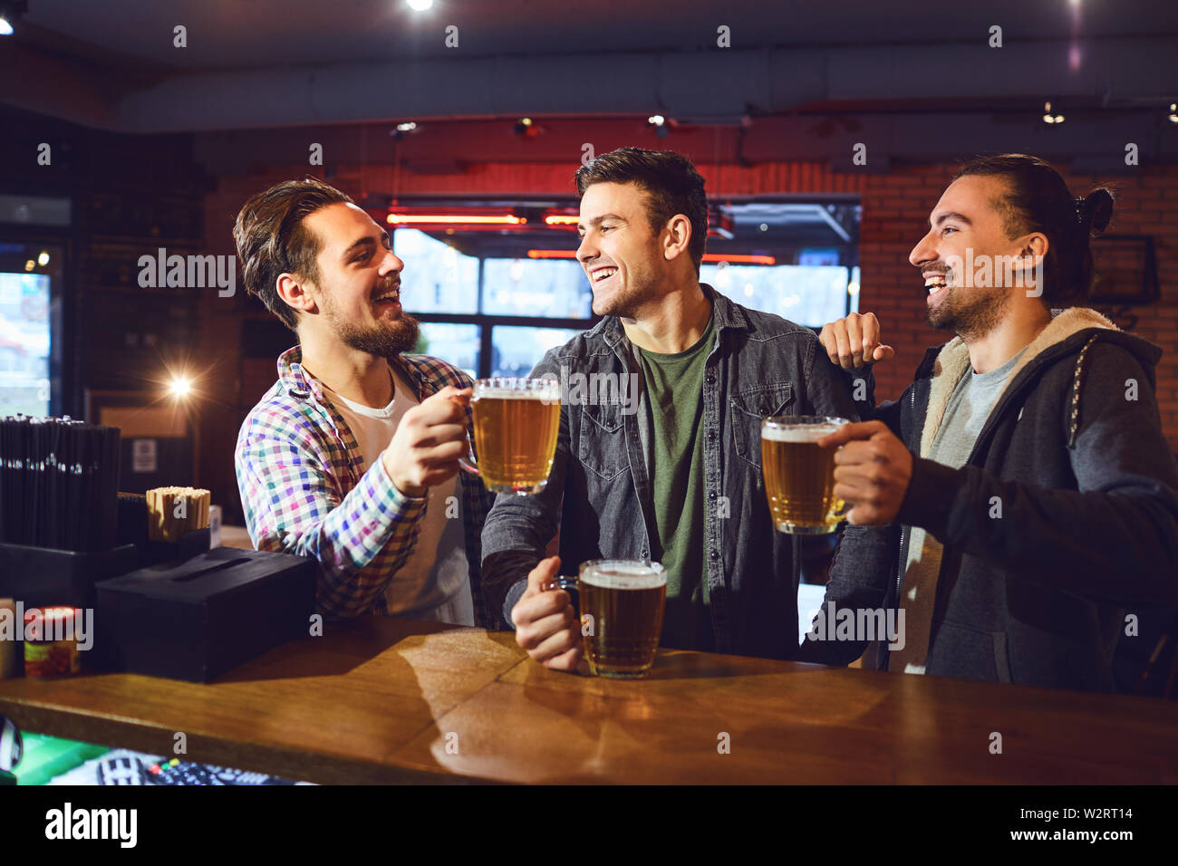 Meeting friends at the bar. Friends drink beer, talk, laugh at the bar ...