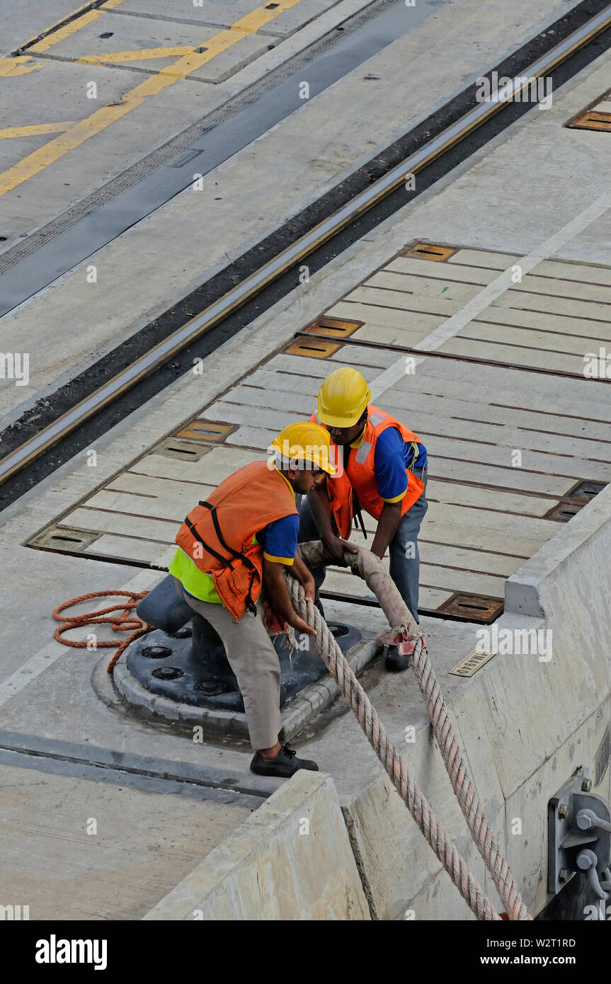 port klang westport, selangor / malaysia - december 27, 2014: two port workers detaching lines of a departing large containership from quay bollard Stock Photo