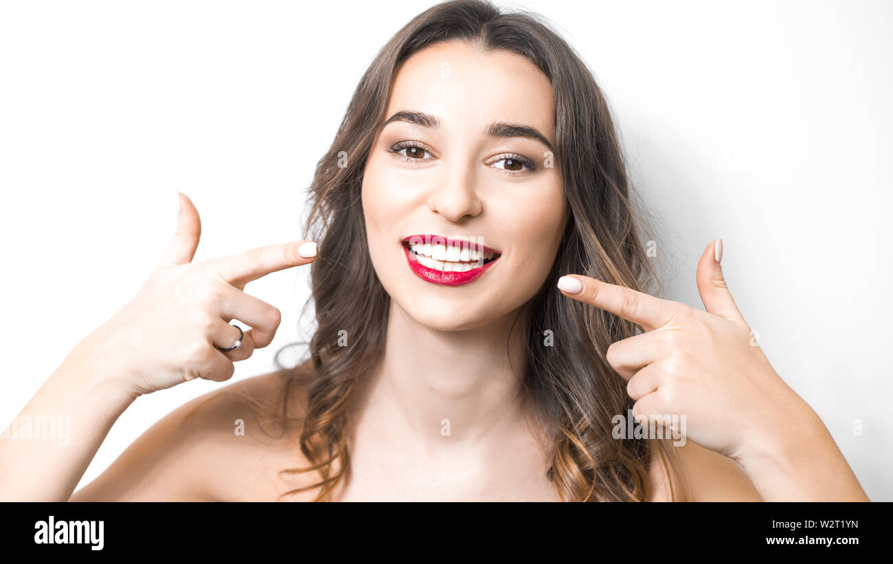 Dentistry concept. Beautiful young woman smiling, showing healthy white teeth, red lipstick. Stock Photo