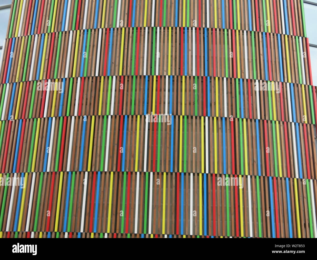 Multi-coloured stripes in rows of cladding on the wall of a modern ...