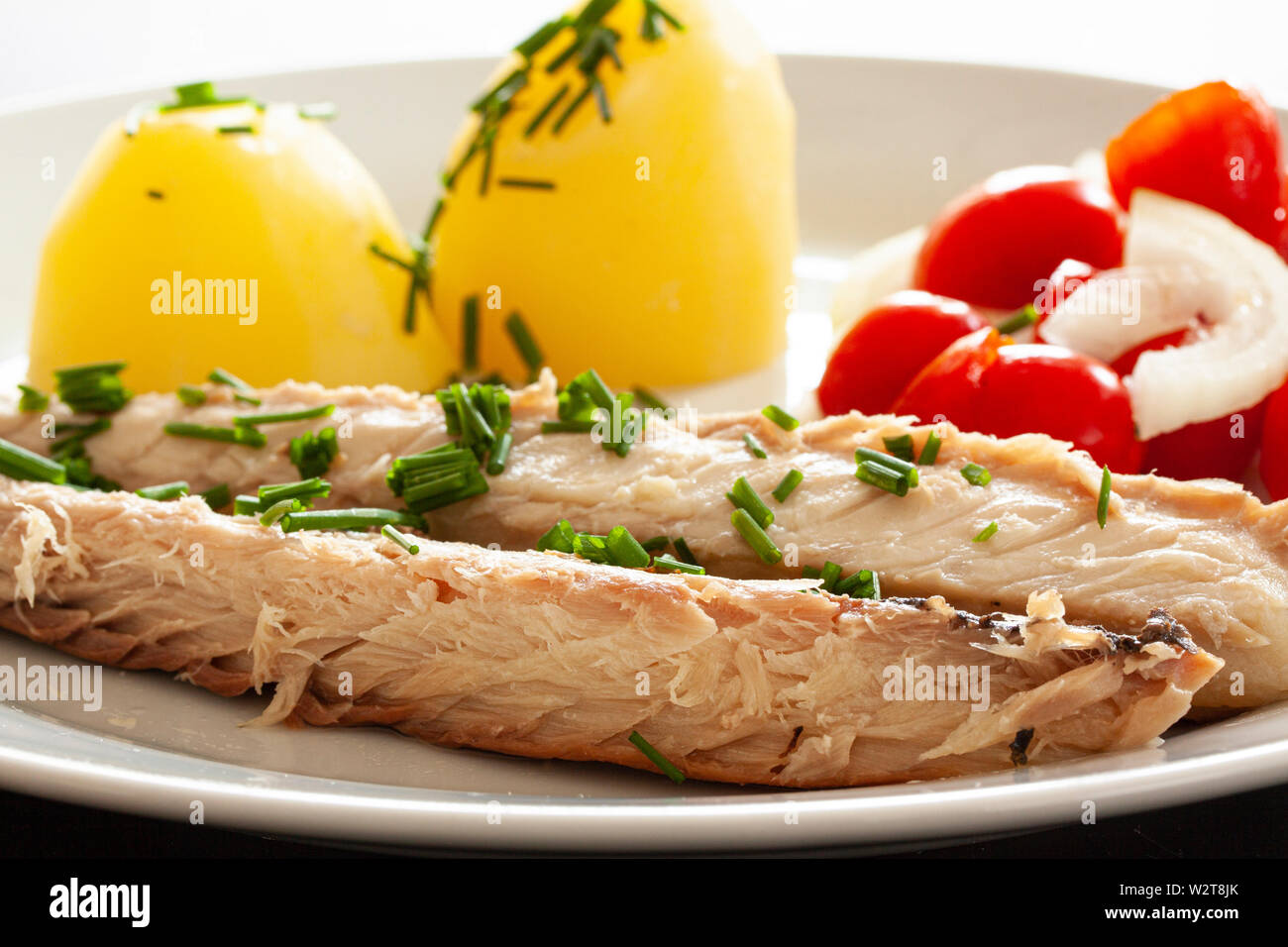 Mackerel fish dish with potatoes, chives and tomato salad. Fatty, oily