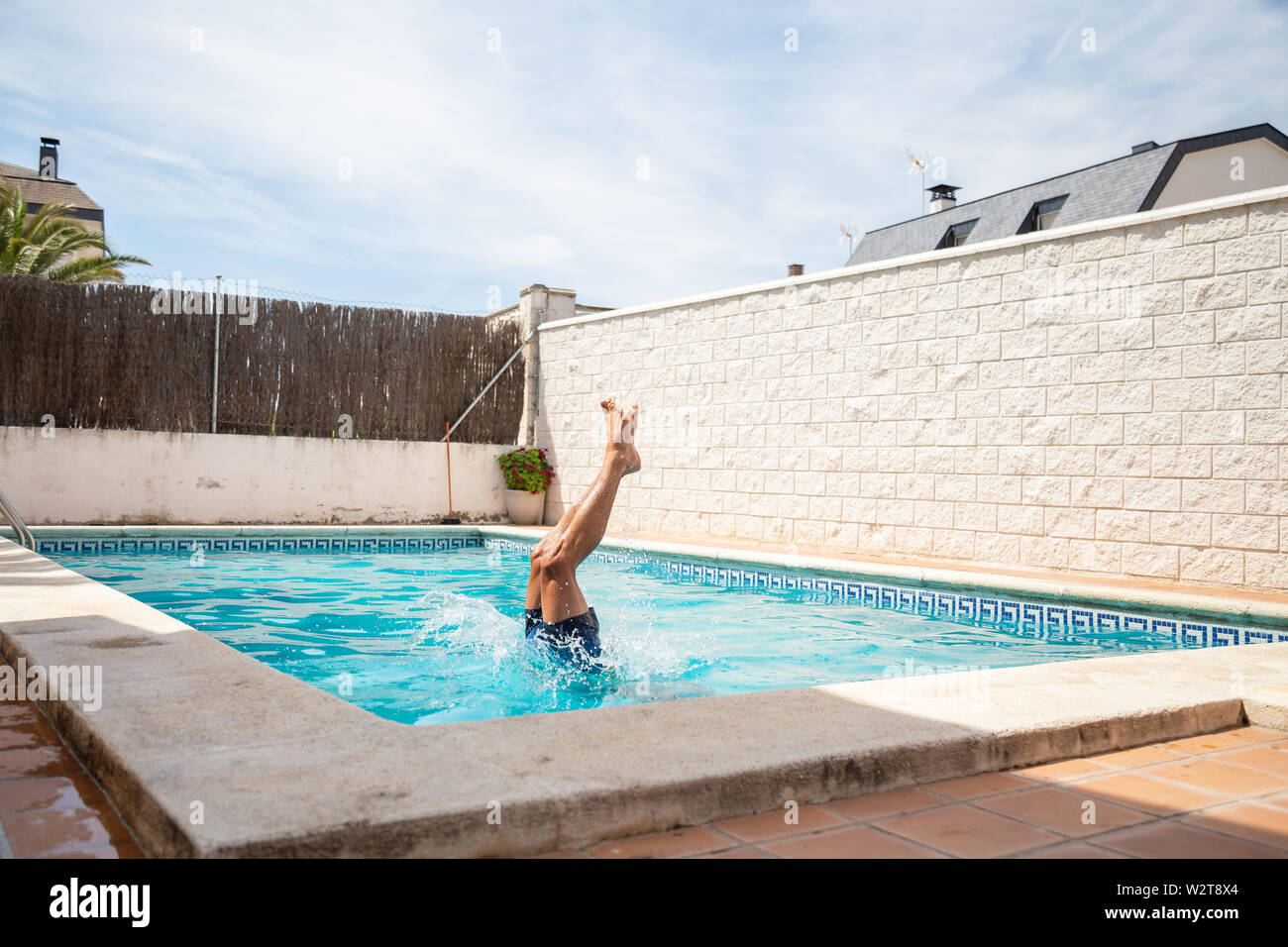 Young fitness man jumping into the water in the pool one day of summer vacation Stock Photo