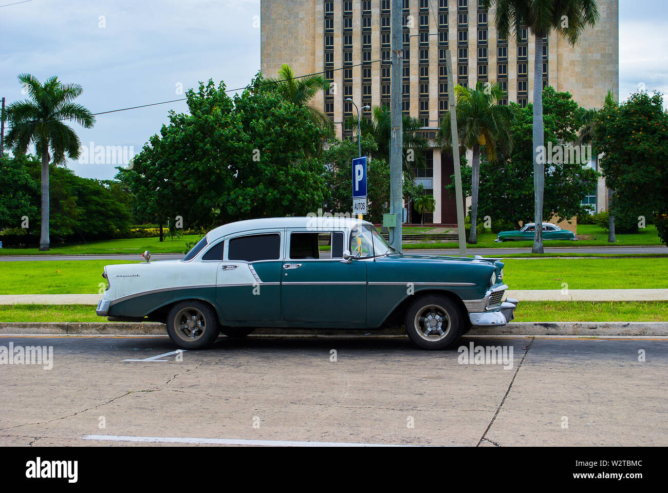 Havana - Cuba / October 16 2011, 1957 green white Chevrolet is parked in the center of Havana with another classic American car passing in the backgro Stock Photo
