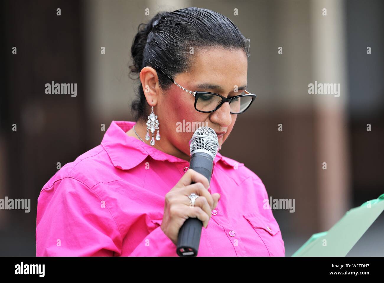 middle aged senior Hispanic Mexican woman talking to a crowd at annual parade in central California, announcing the manes and such to parade goers Stock Photo