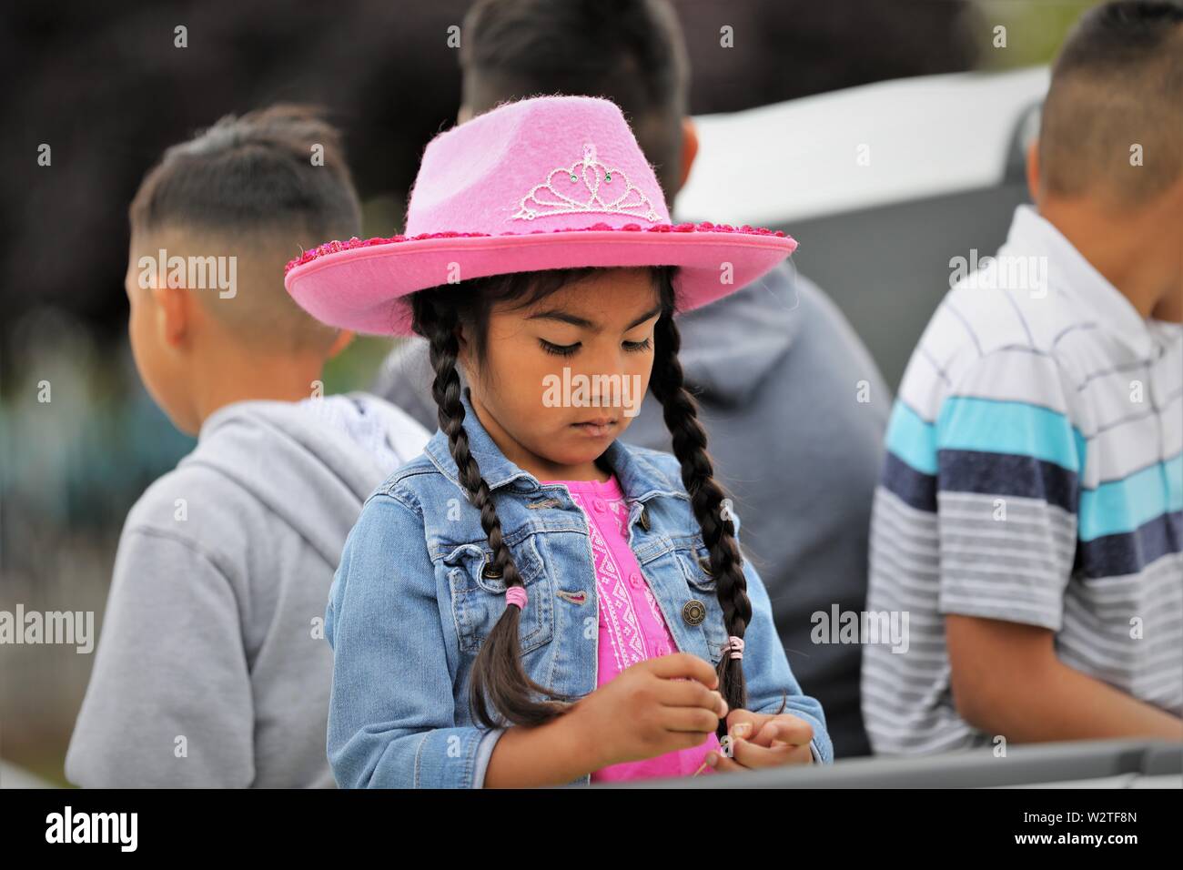 Kids at public parade celebrating their Mexican heritage ranching and cowboy and cowgirl heritage in California with pink hat Stock Photo