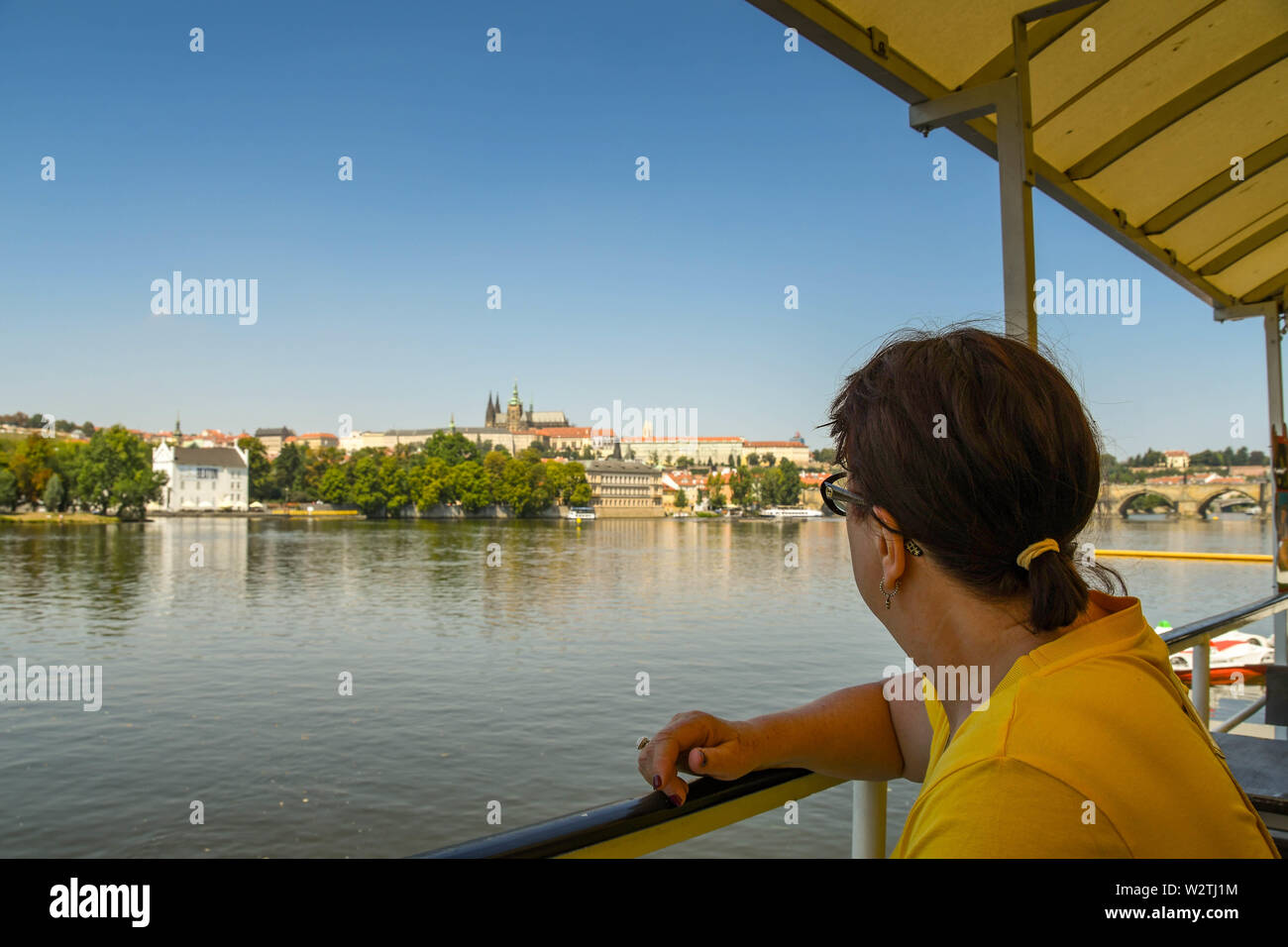 PRAGUE, CZECH REPUBLIC - AUGUST 2018: Person on a river cruise boat looking out over the River Vltava to the skyline of Prague. Stock Photo