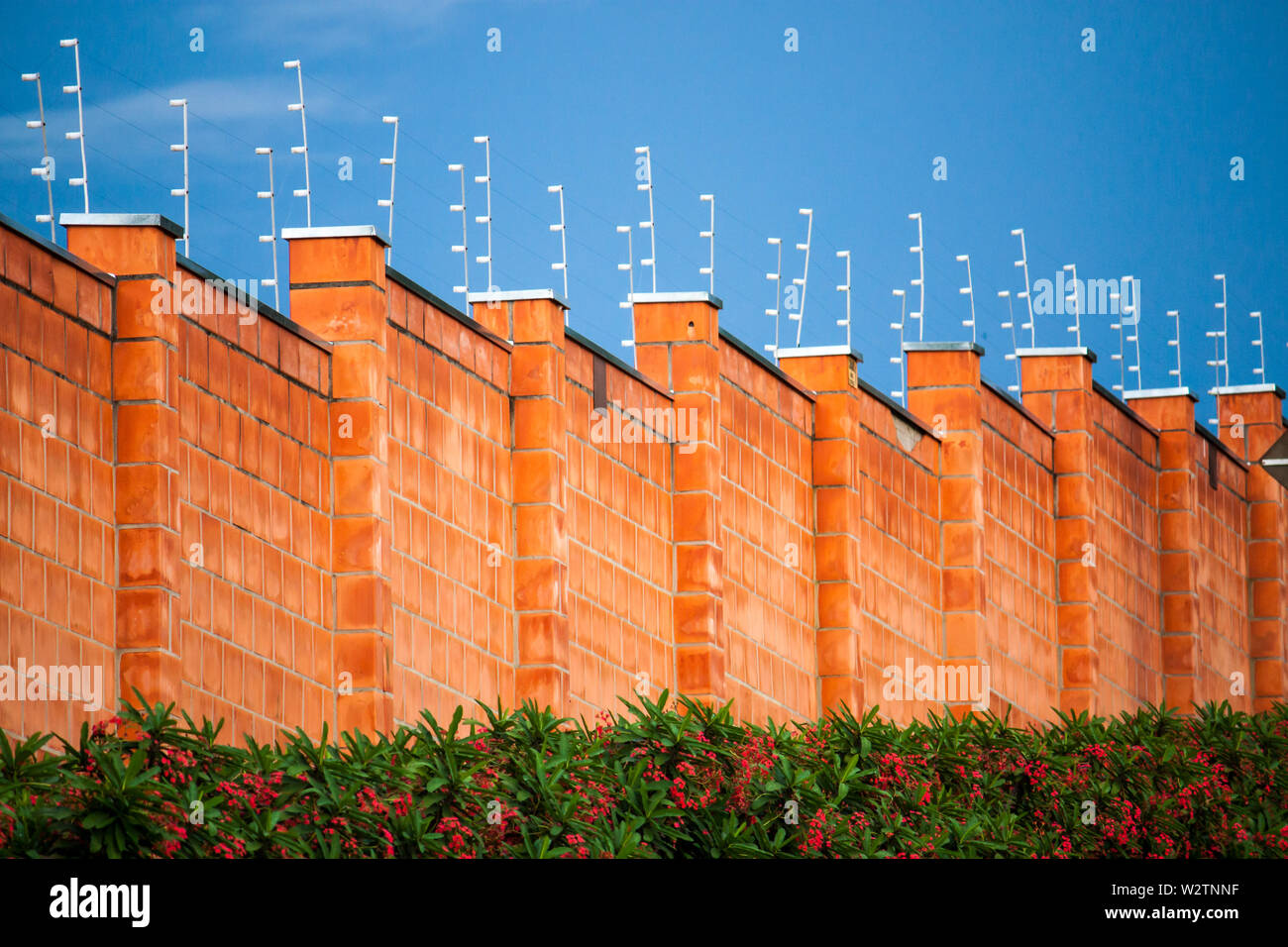 Security electric fence and red brick wall in a residential gated