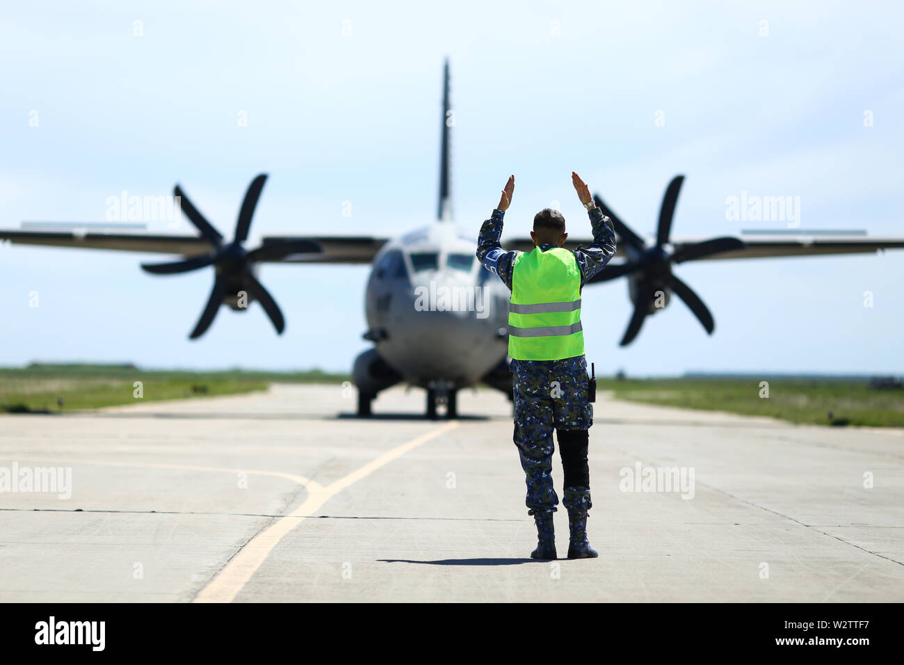 Boboc, Romania - May 22, 2019: Ground personnel is aircraft marshalling an Alenia C-27J Spartan military cargo plane from the Bulgarian Air Force that Stock Photo
