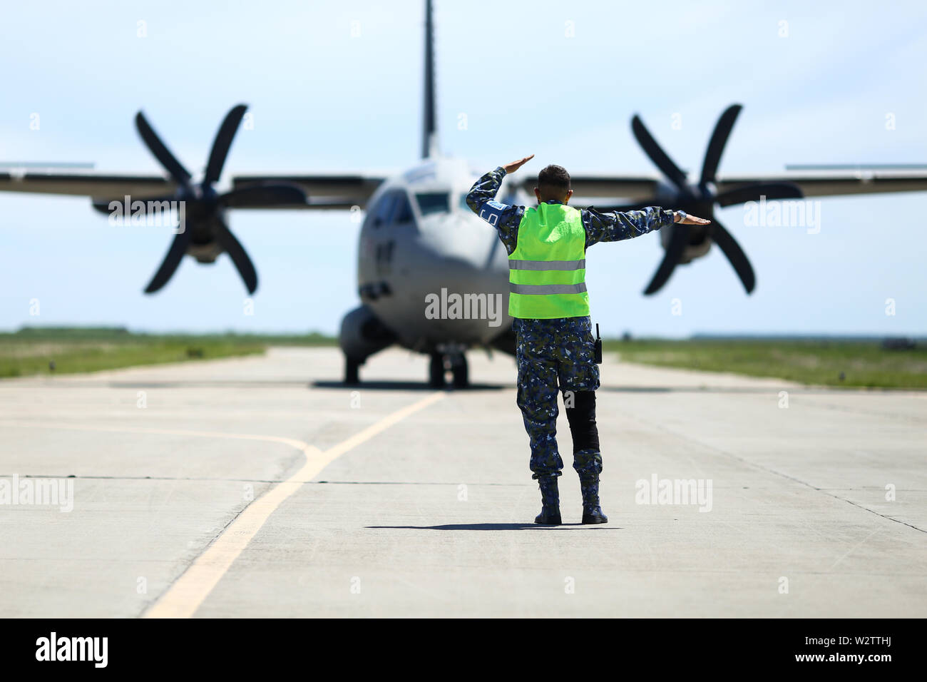 Boboc, Romania - May 22, 2019: Ground personnel is aircraft marshalling an Alenia C-27J Spartan military cargo plane from the Bulgarian Air Force that Stock Photo