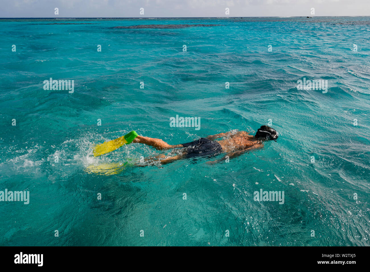Persons with yellow flippers snorkelling in the turquoise lagoon of Aitutaki, Cook Islands, Polynesia Stock Photo