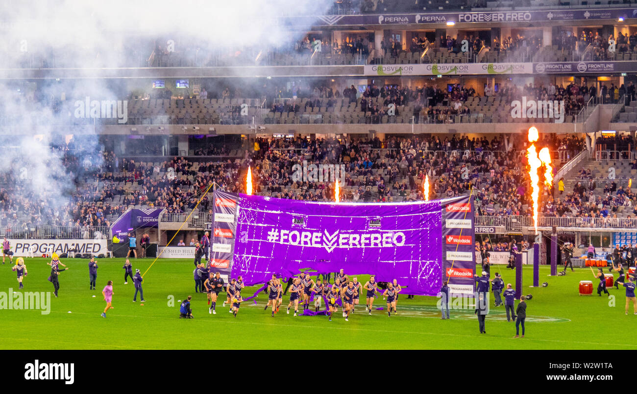 Fremantle Dockers football players running through banner  in Western Derby AFL game at Optus Stadium Perth Western Australia. Stock Photo