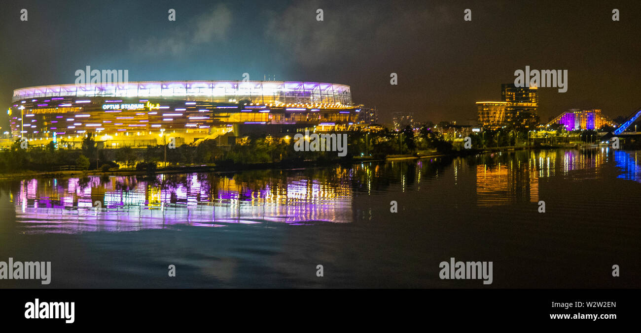Optus Stadium on the banks of the Swan River lit up at night in Fremantle Dockers football club colours Perth Western Australia. Stock Photo