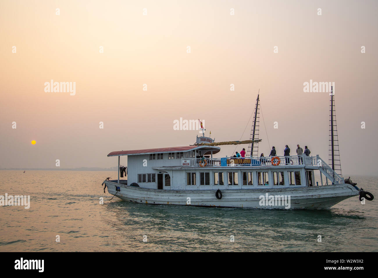 Halong Bay, Vietnam - December24, 2013:  Tourist boat navigating at Halong Bay with a few people regarding the sunset. Stock Photo