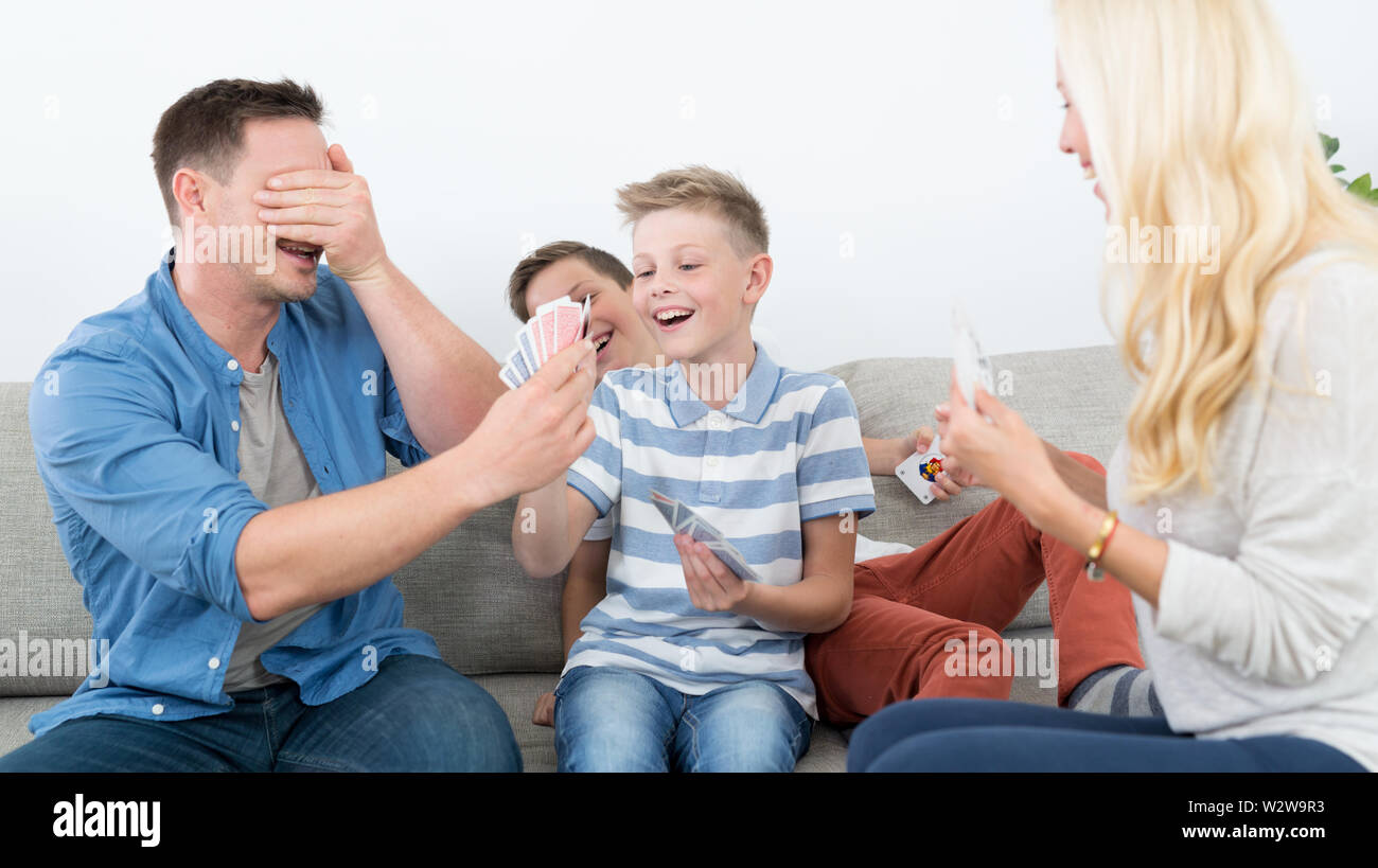 Happy young family playing card game at home Stock Photo - Alamy