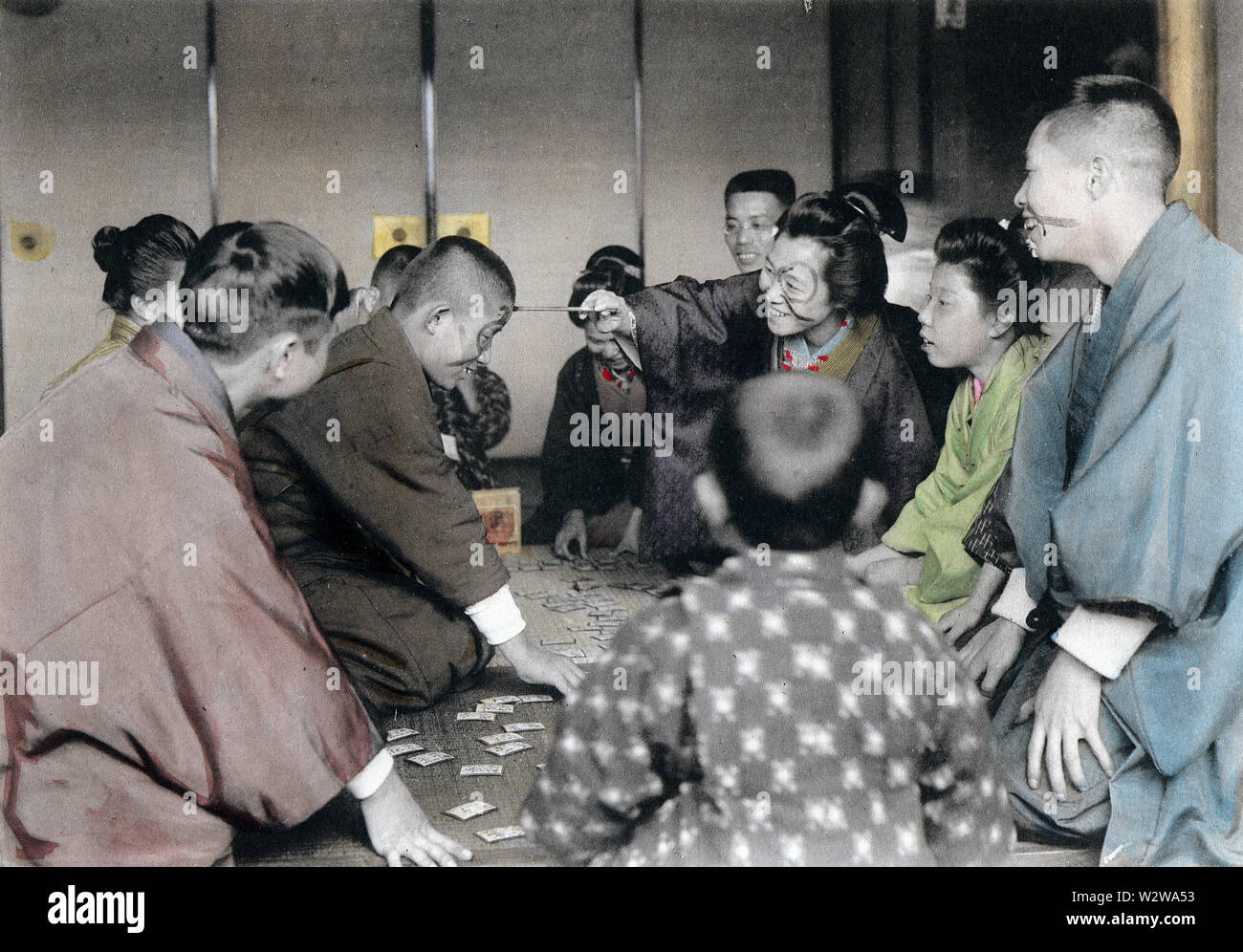 [ 1900s Japan - Japanese New Year - Playing Karuta ] —   Losers in the card game of karuta (see New Year Celebrations 18) get ink painted on their face.   This image is part of The New Year in Japan, a book published by Kobe-based photographer Kozaburo Tamamura in 1906 (Meiji 39).  20th century vintage collotype print. Stock Photo