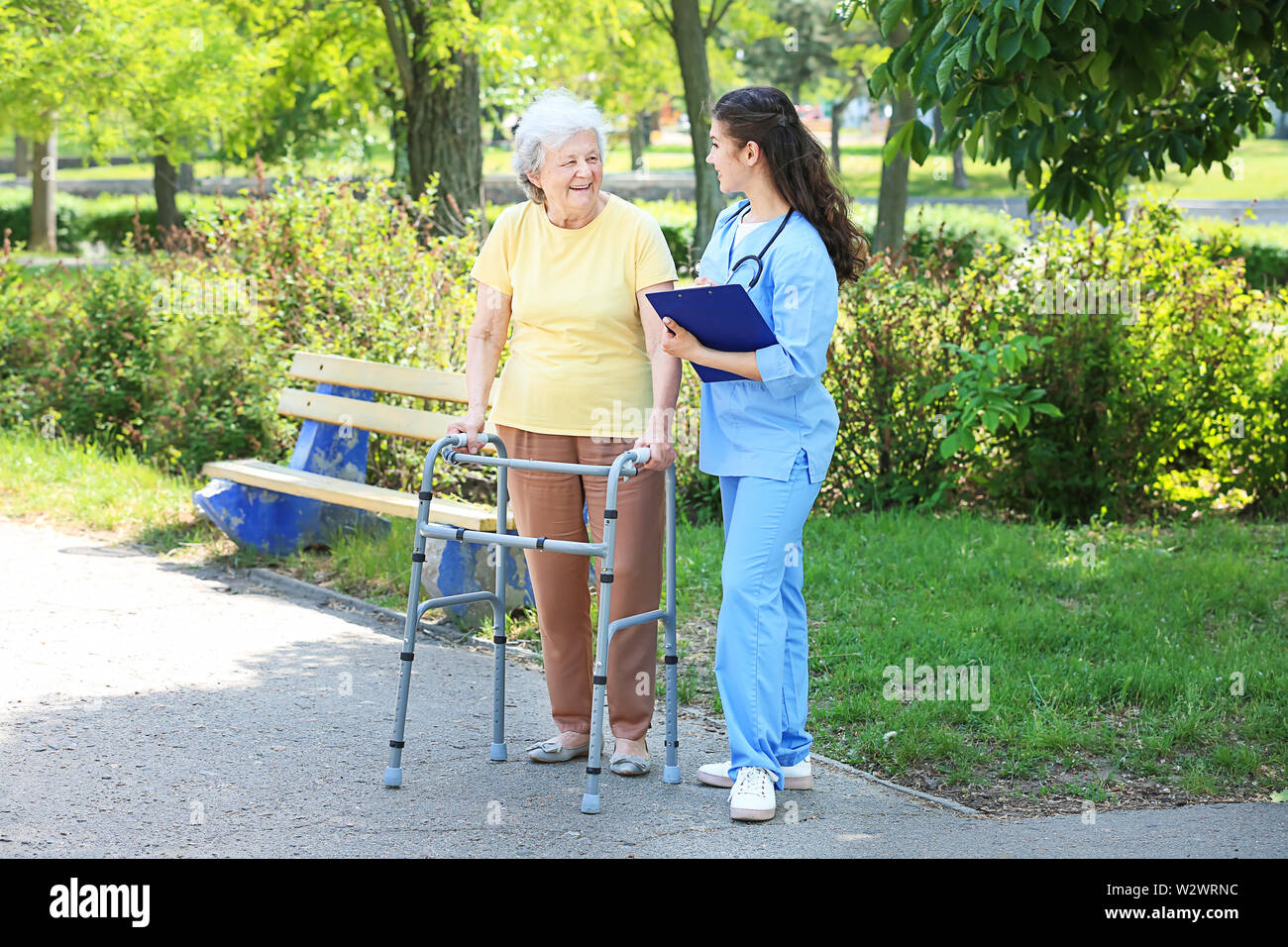 Caregiver walking with senior woman in park Stock Photo Alamy