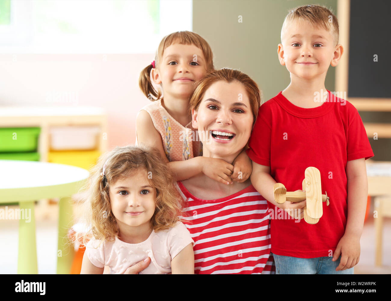 Nursery teacher with cute little children in kindergarten Stock Photo