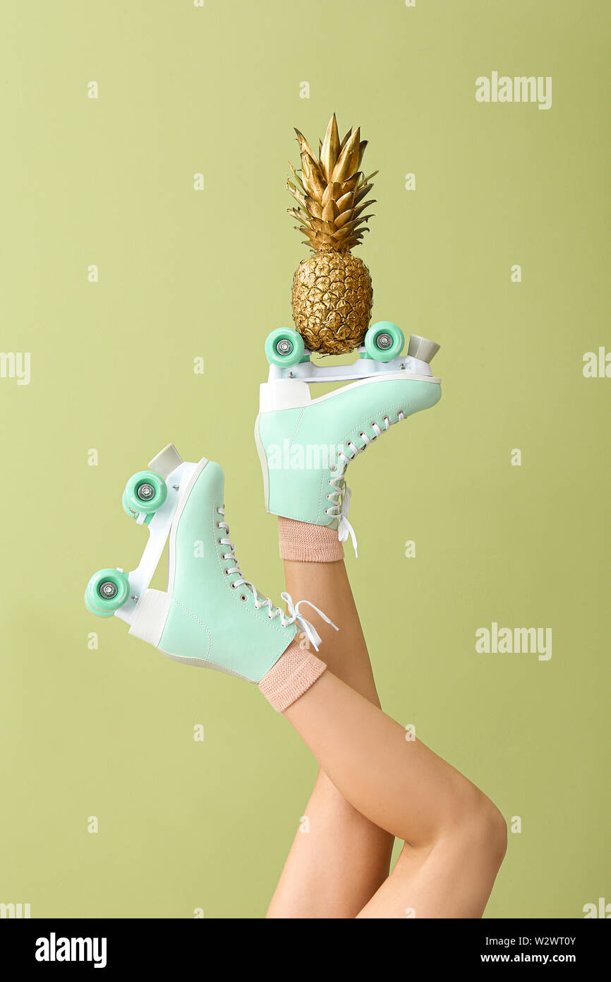 Legs of woman in roller skates and with golden pineapple on color  background Stock Photo - Alamy