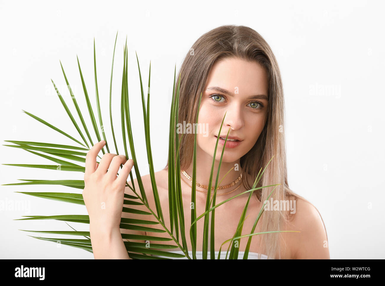 Beautiful young woman with tropical leaf on white background Stock ...
