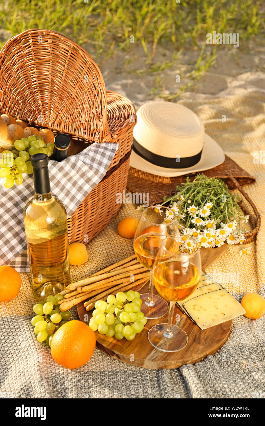 Wicker basket with tasty food and drink for romantic picnic on beach ...