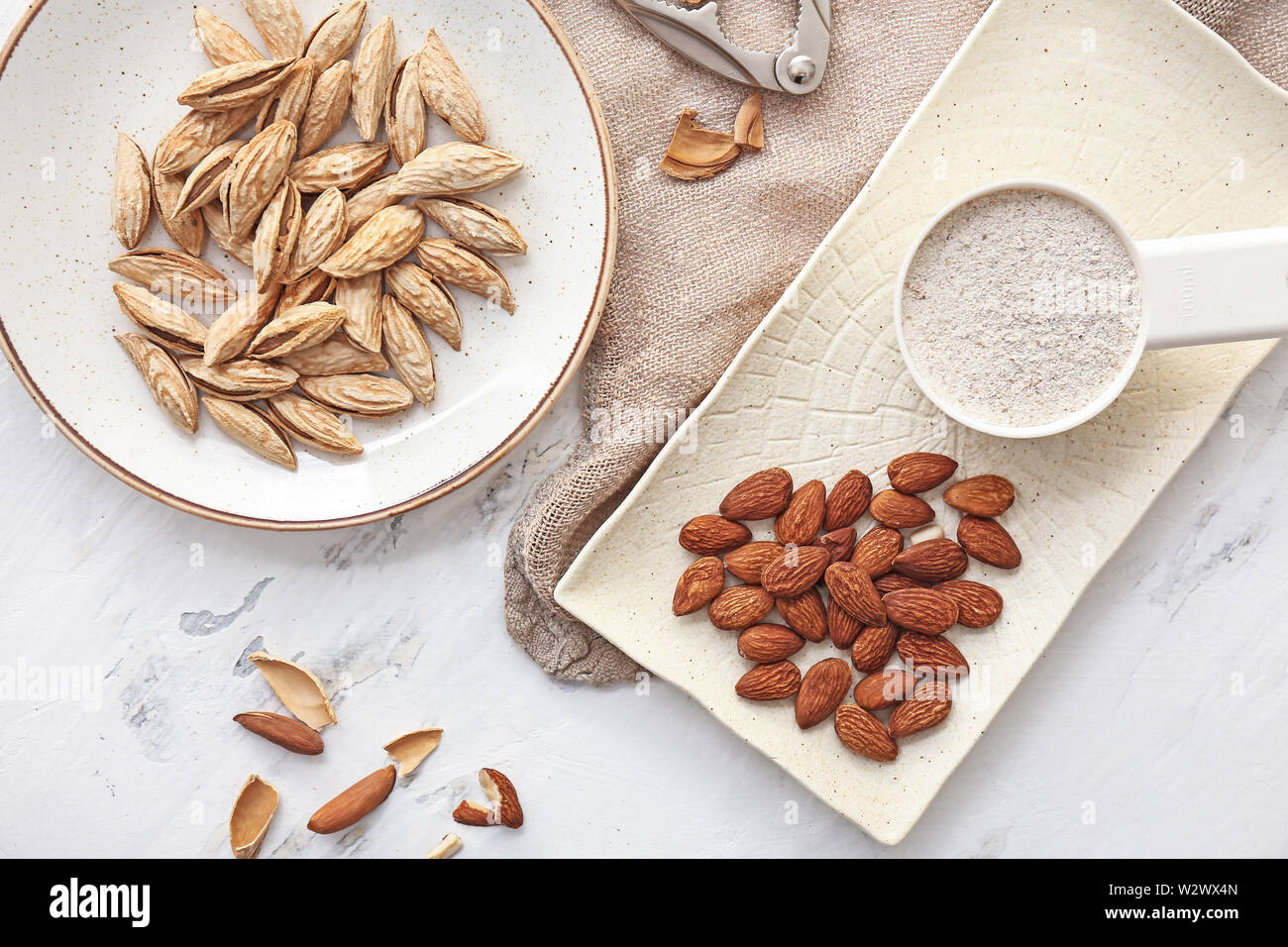 Composition with almonds and flour on white table Stock Photo - Alamy