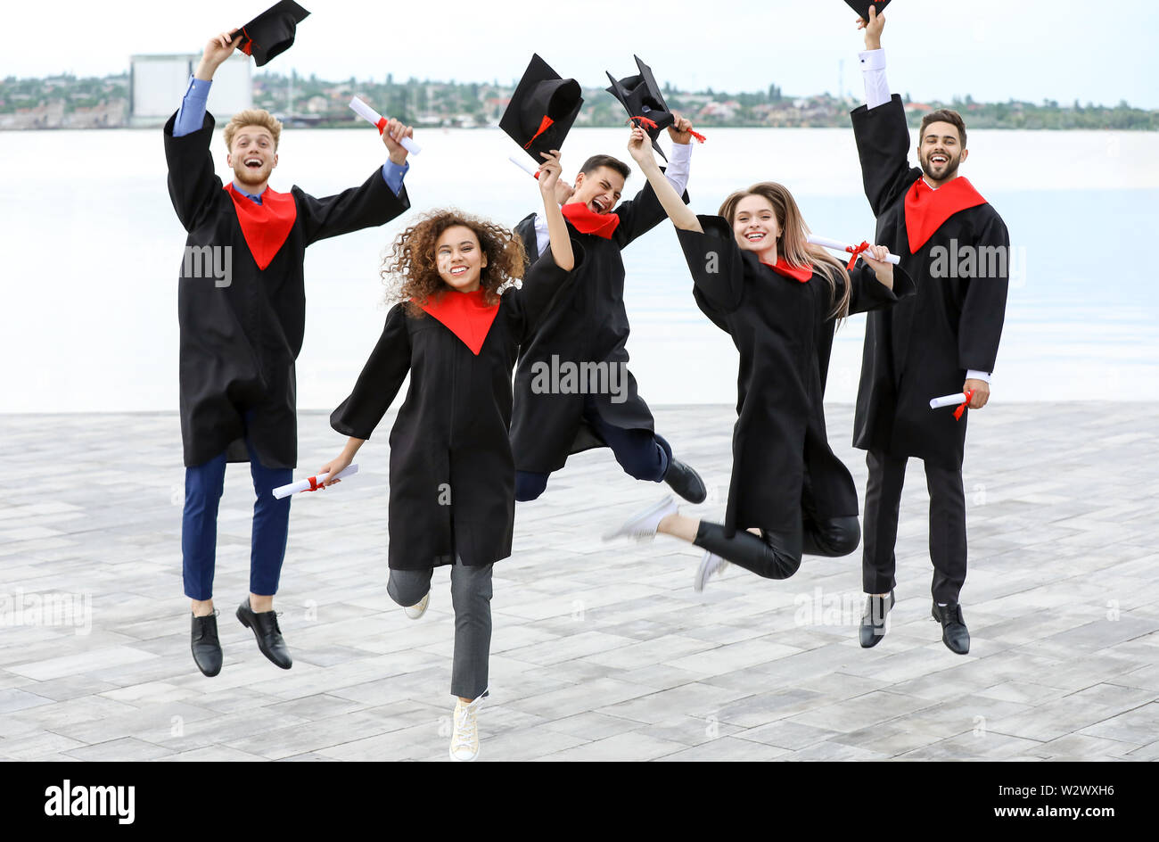Happy students in bachelor robes outdoors on graduation day Stock Photo ...