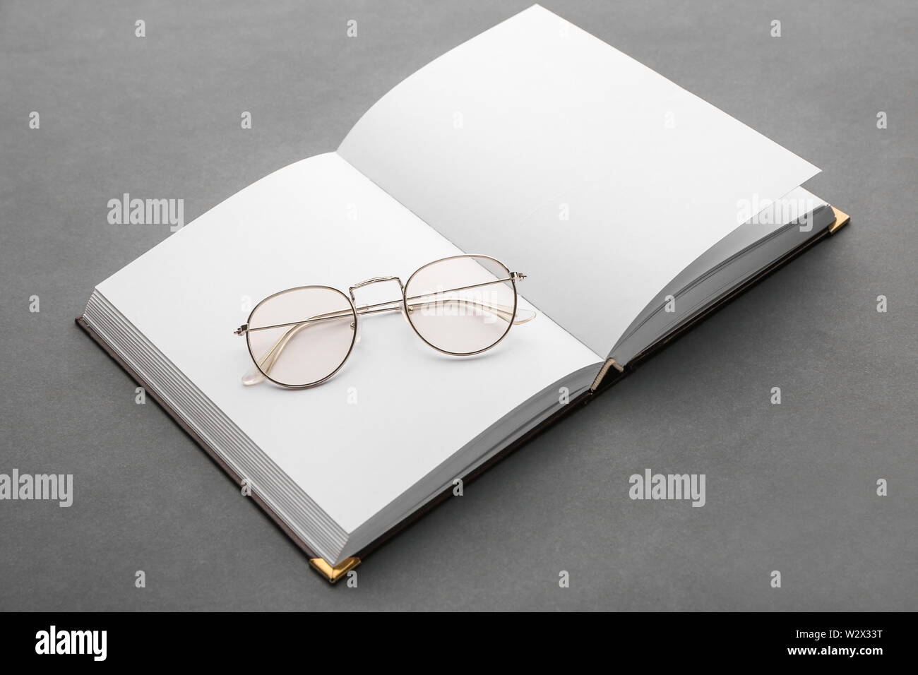 Open book with eyeglasses on grey background Stock Photo