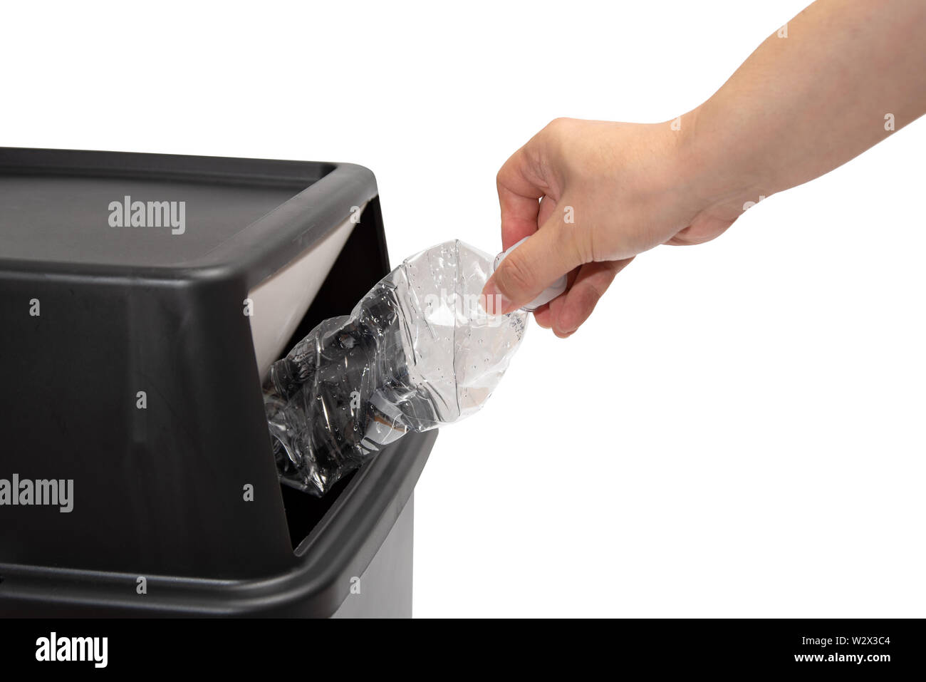 The hand of a man who throws a plastic bottle into a trash can. waste ...