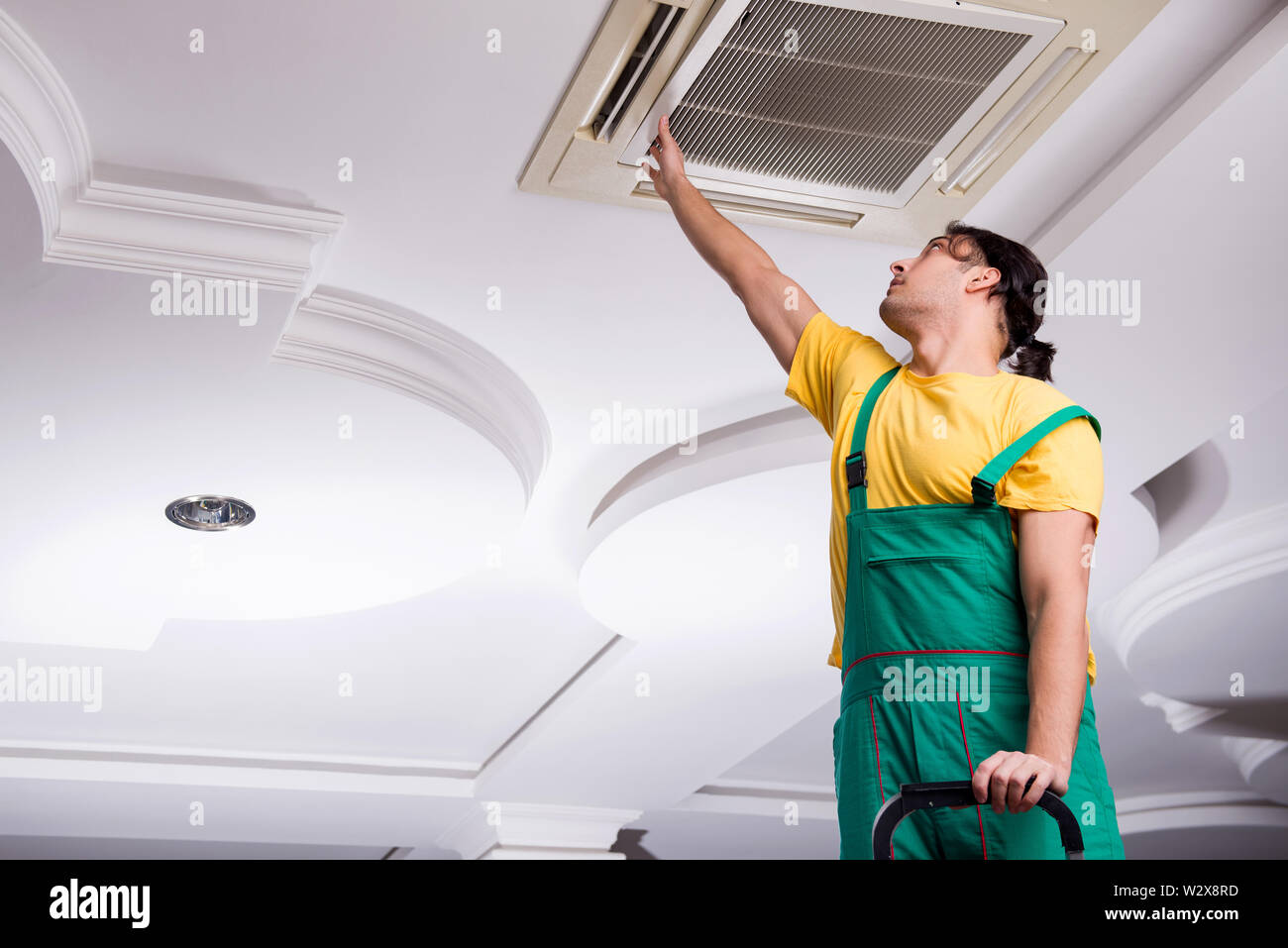 The Young Repairman Repairing Ceiling Air Conditioning Unit