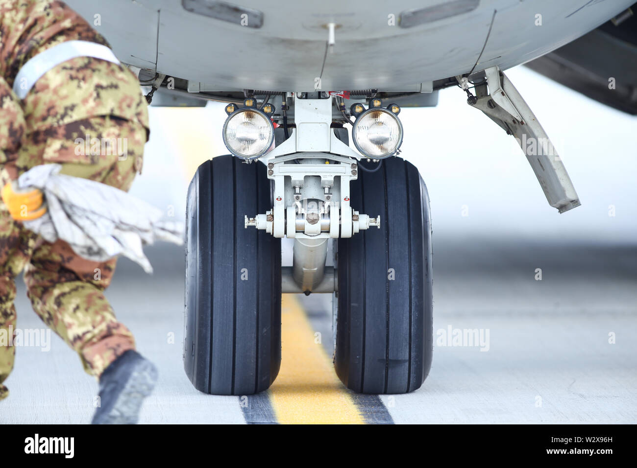 An army mechanic is inspecting the landing gear of a military cargo plane. Stock Photo