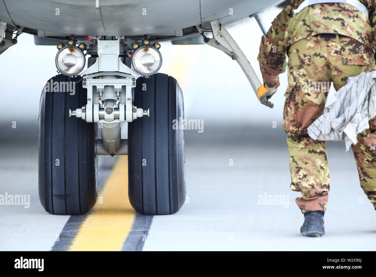 An army mechanic is inspecting the landing gear of a military cargo plane. Stock Photo